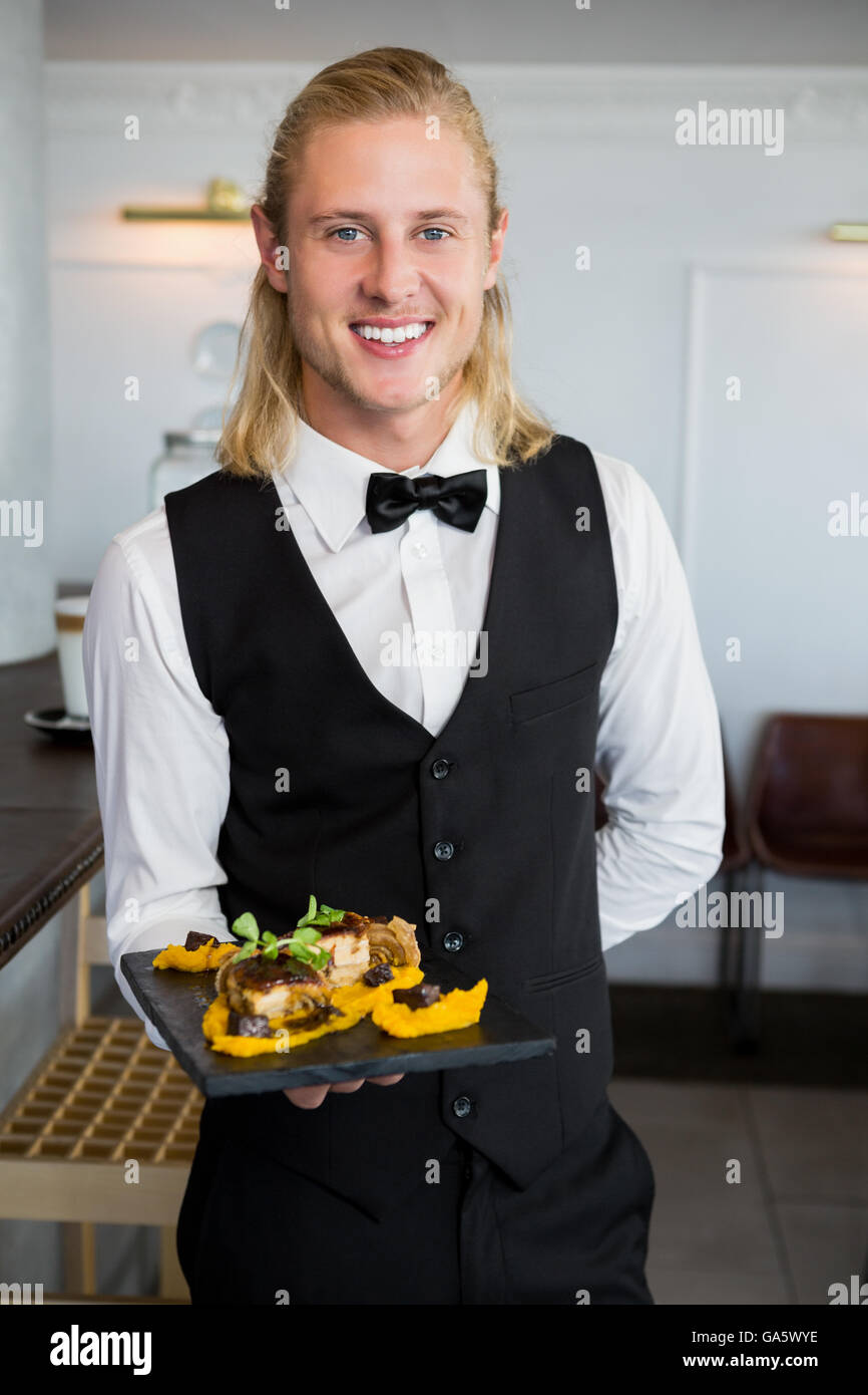 Waiter holding a plate of food in restaurant Banque D'Images