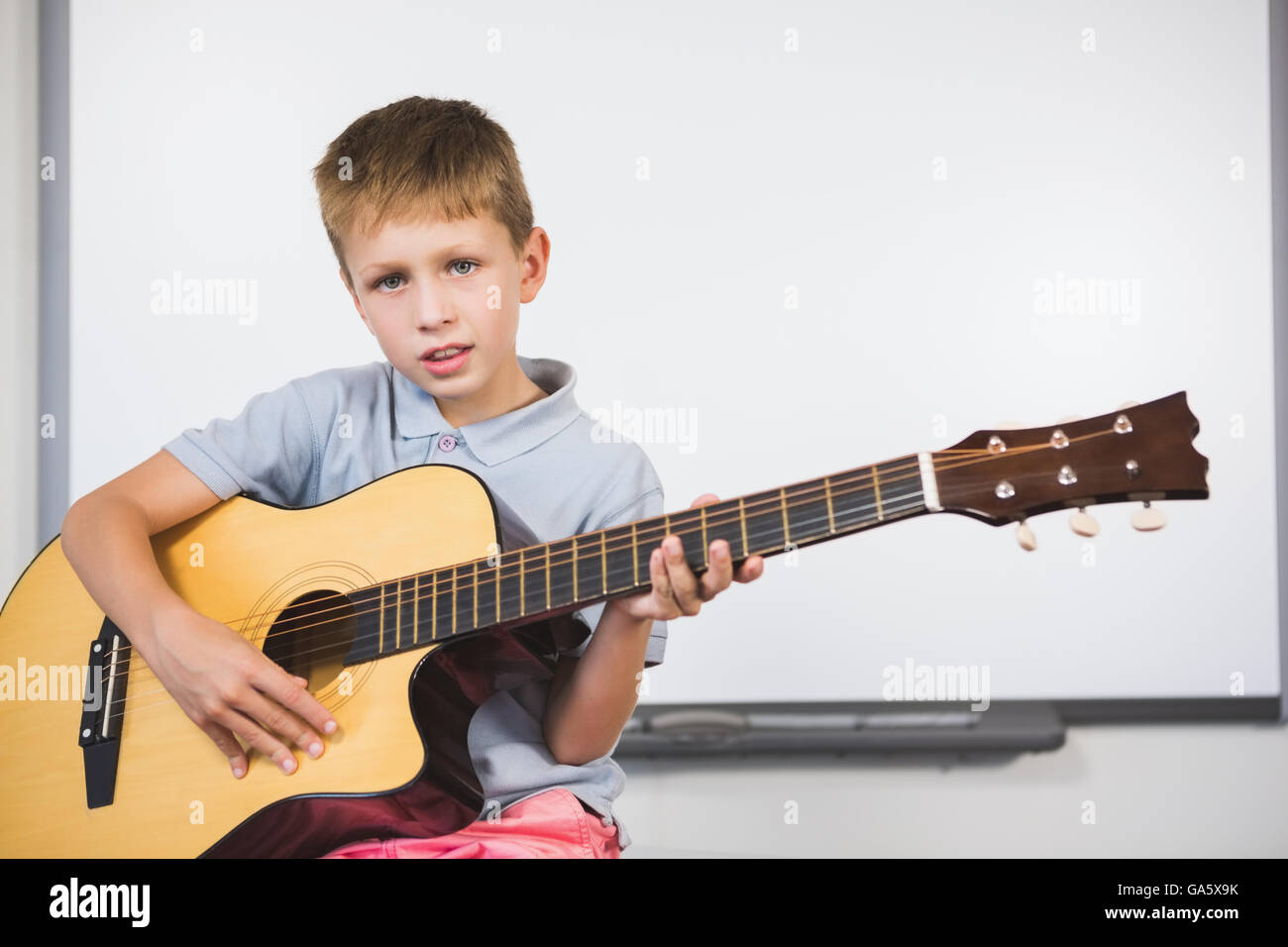 Portrait d'écolier à jouer de la guitare en classe Banque D'Images