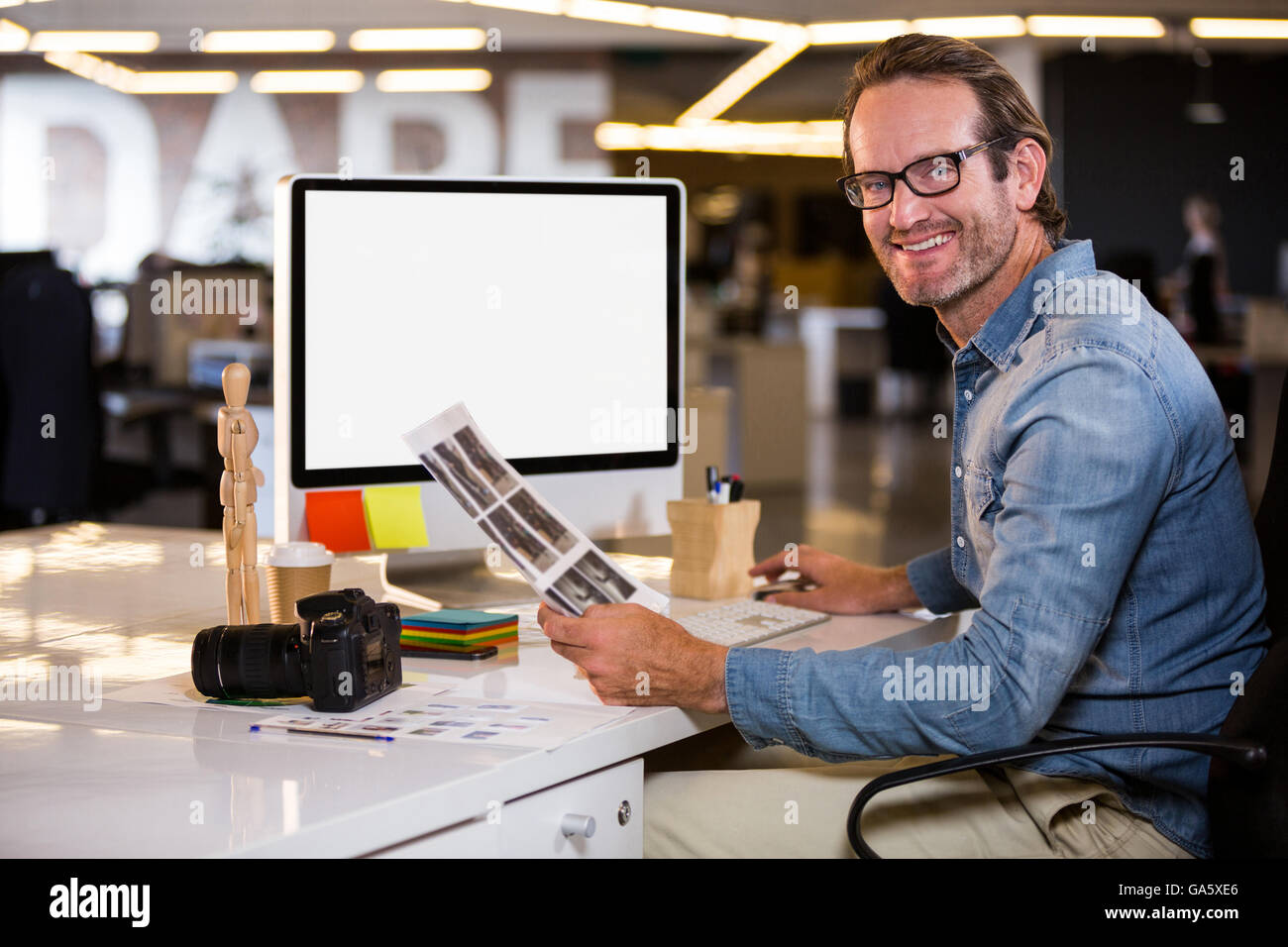 Smiling photo editor assis à l'ordinateur 24 Banque D'Images