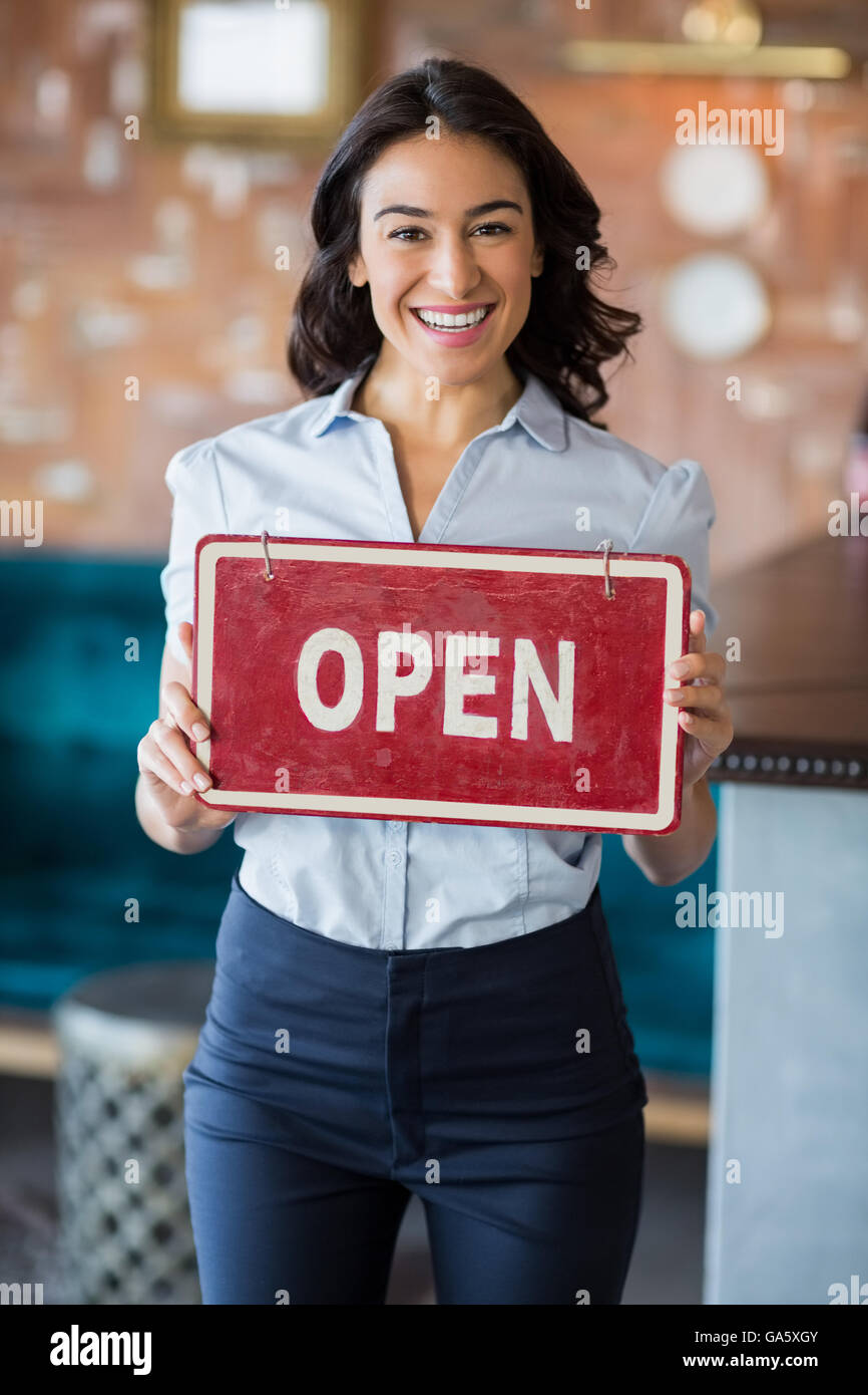 Smiling waitress holding un conseil avec open sign in restaurant Banque D'Images