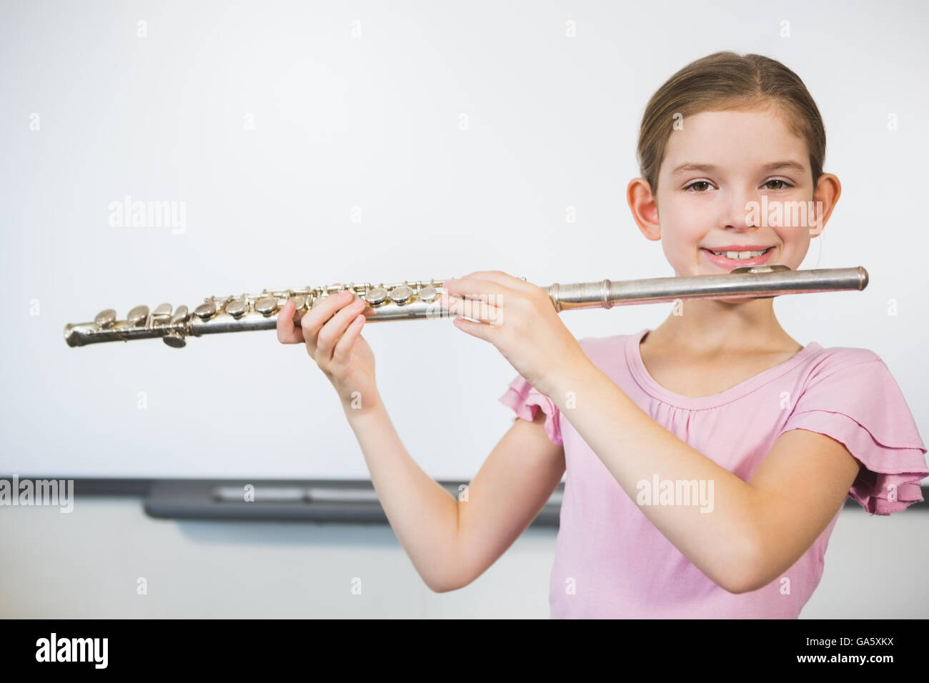 Portrait of smiling schoolgirl jouer flûte en classe Banque D'Images