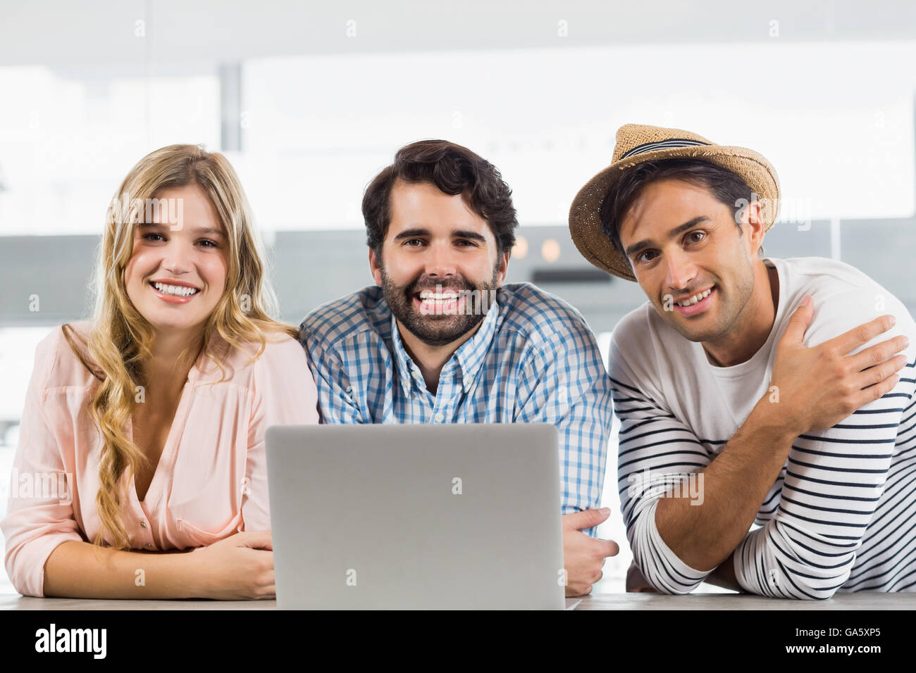 Portrait of smiling woman et deux hommes using laptop Banque D'Images