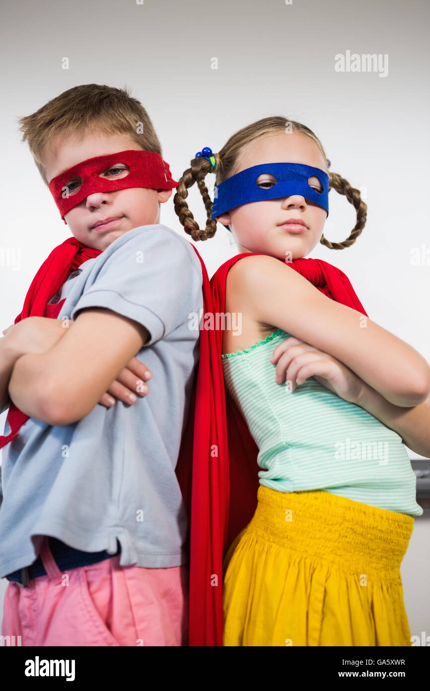 Garçon et fille debout avec bras croisés et faire semblant d'être un super héros Banque D'Images