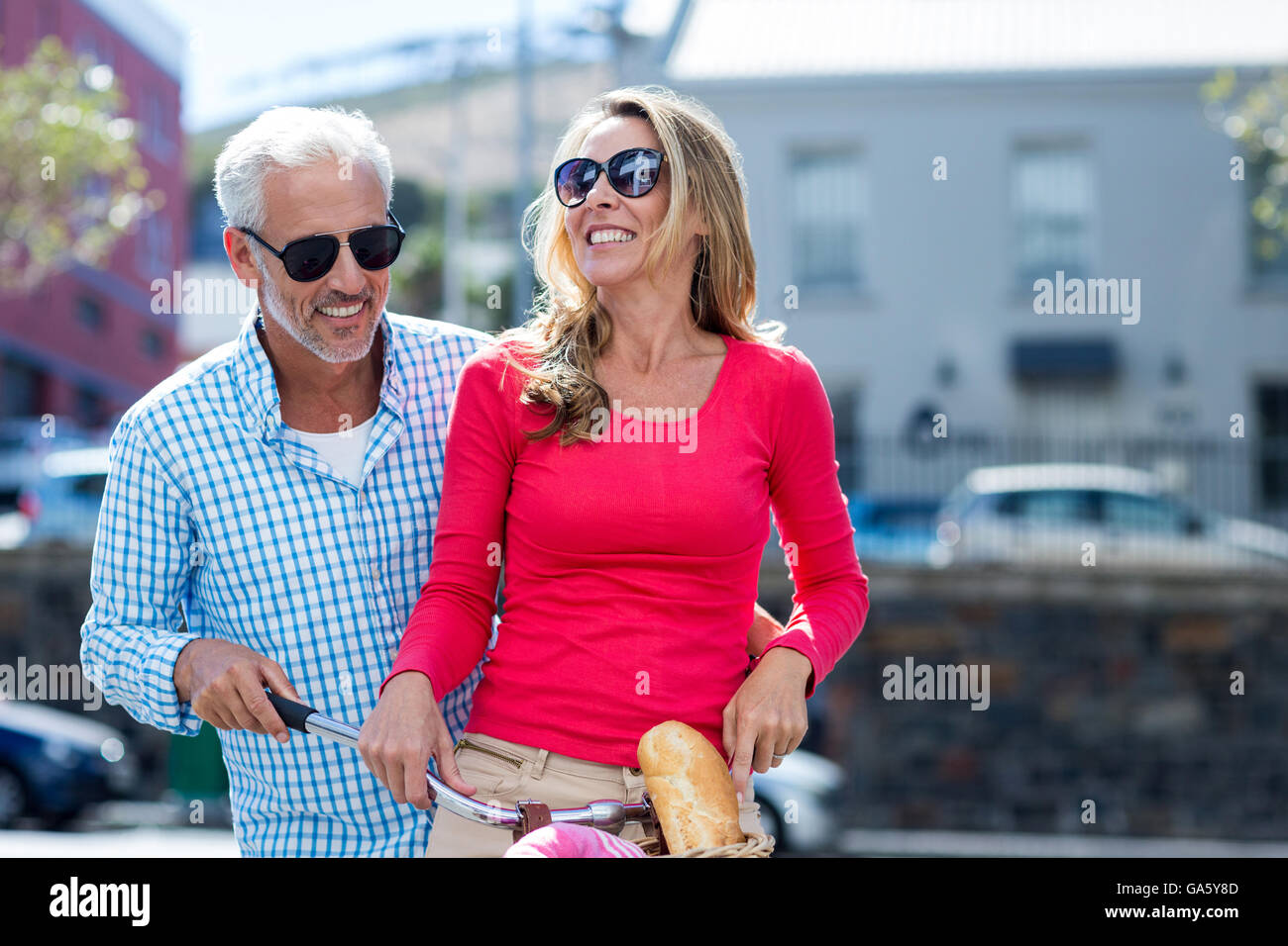 Young couple riding bicycle on city street Banque D'Images