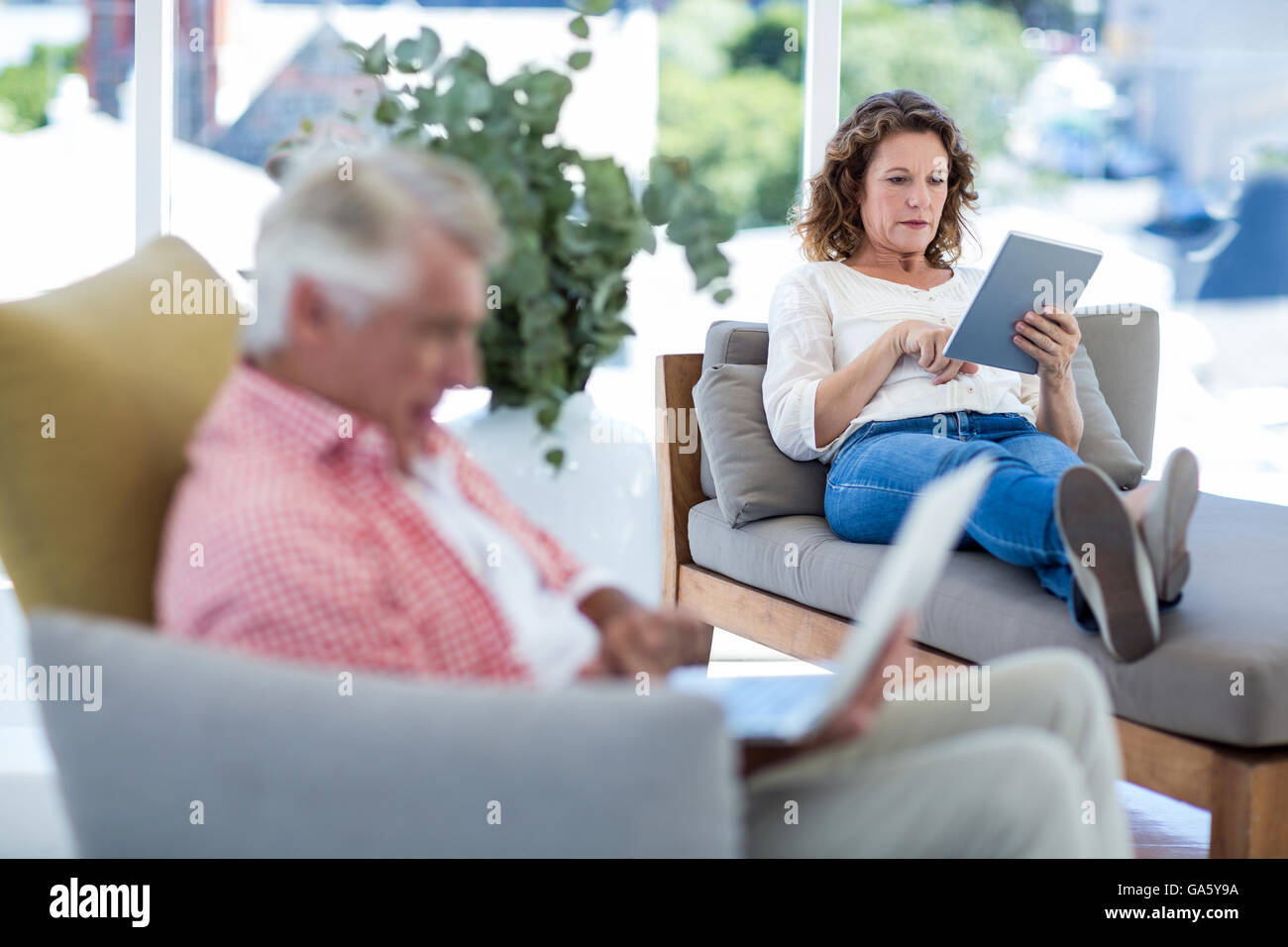 Woman using digital tablet tout en vous relaxant sur le siège Banque D'Images
