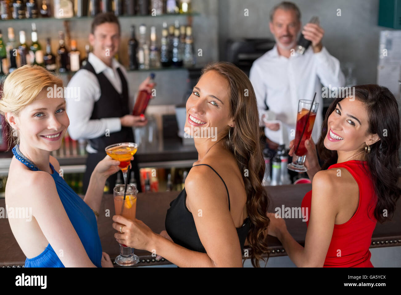 Happy female friends holding verre de cocktail au comptoir du bar Banque D'Images