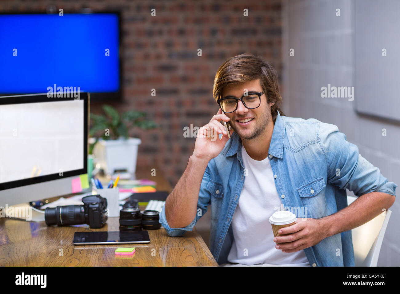 Young man talking on mobile phone in office Banque D'Images