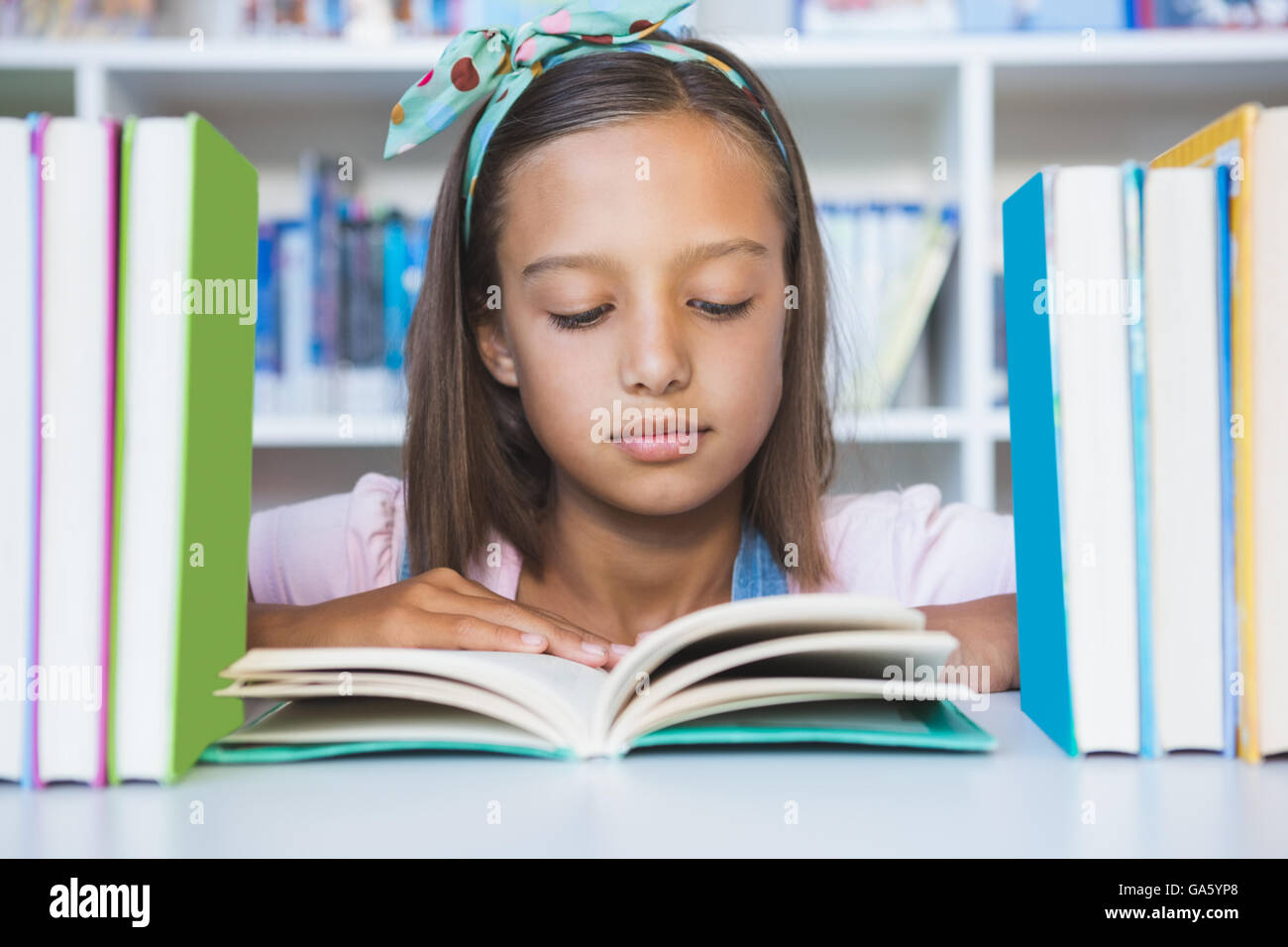School girl reading a book in library Banque D'Images