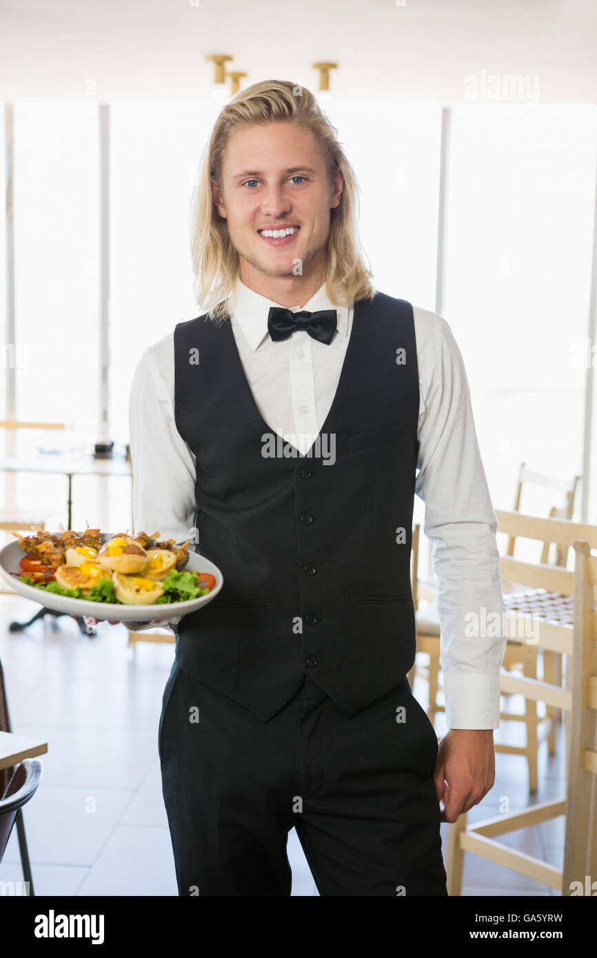Waiter holding a plate of food in restaurant Banque D'Images