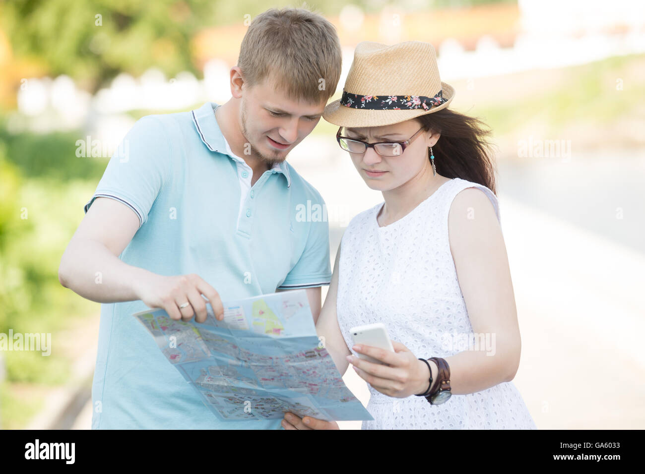 Beau couple de déplacement s'est perdu et la recherche d'emplacement sur la carte. L'homme en bleu t-shirt looking at map sur voyage d'été Banque D'Images