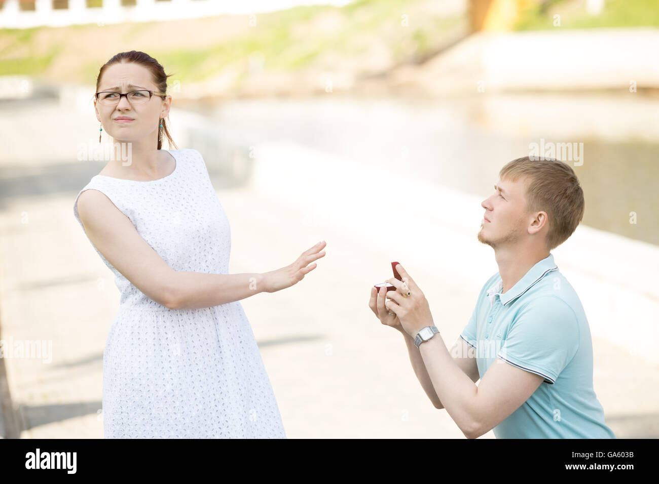 Femme refusant proposition de mariage. De graves beau jeune homme debout sur son genou offrant une boîte avec bague de fiançailles Banque D'Images