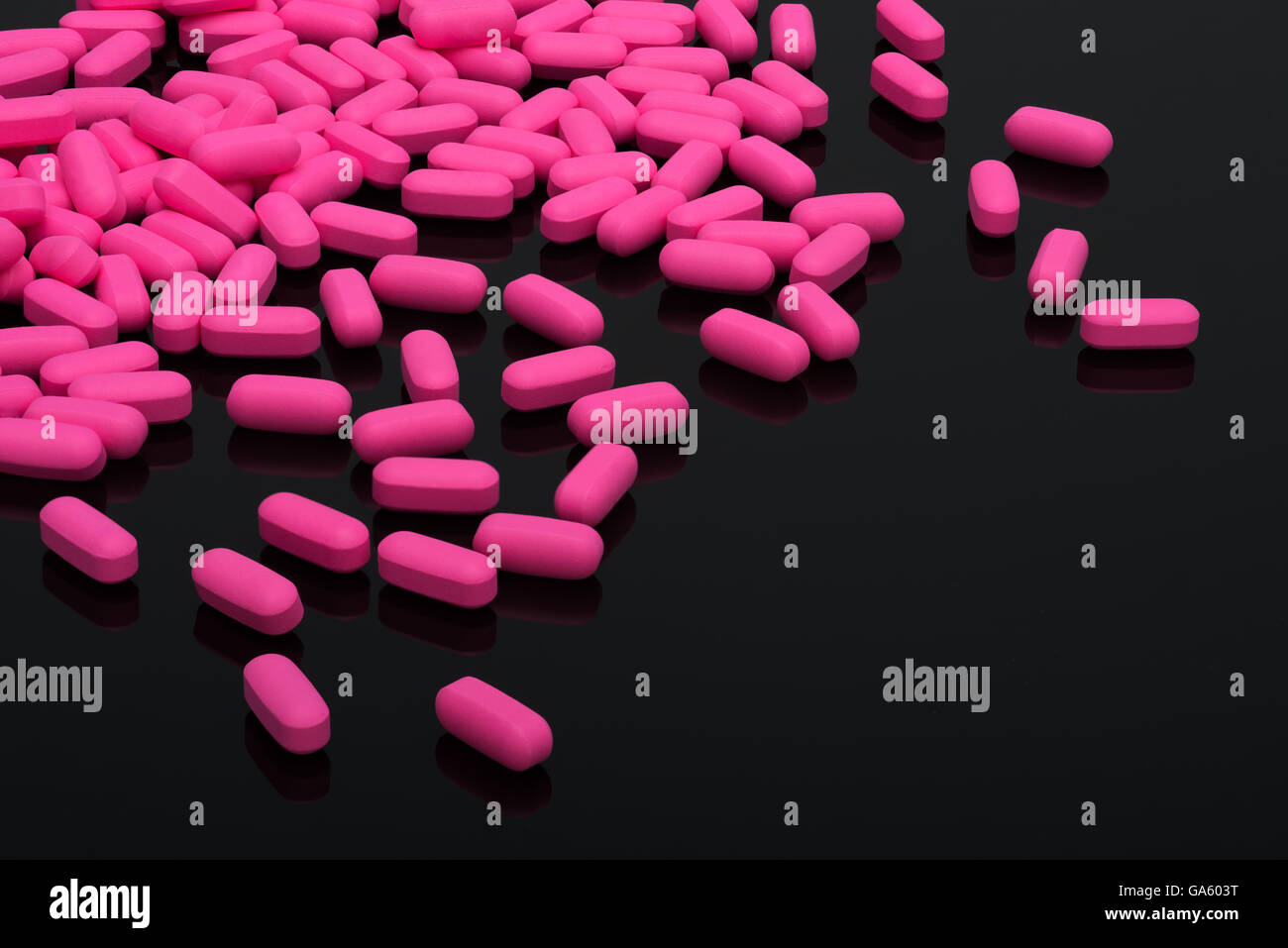 Migraine comprimés, capsules de vitamines rose sur fond noir Banque D'Images