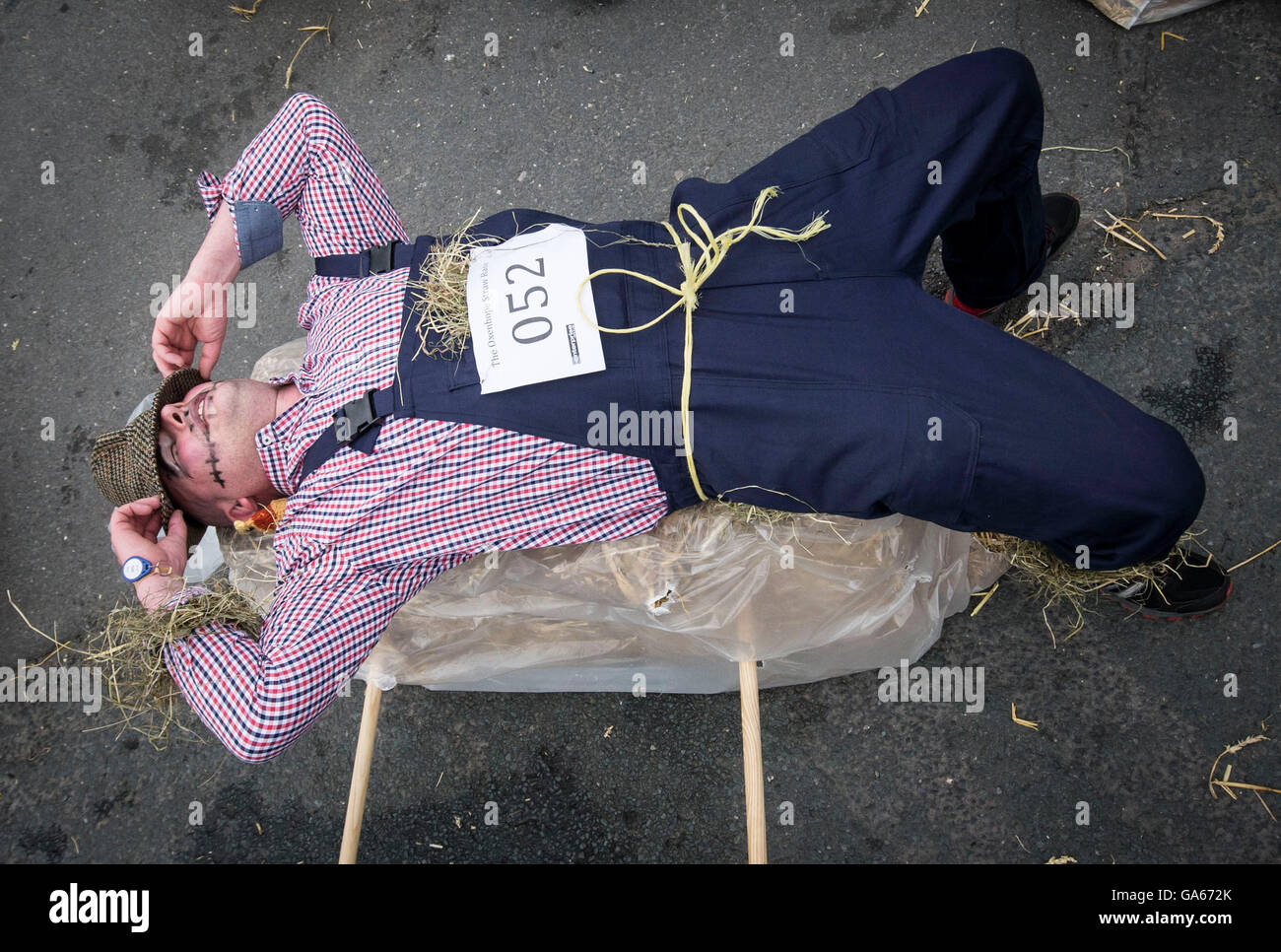 Un concurrent prend part à la ferme de la course de la paille dans le Yorkshire, qui consiste à courir en robe de soirée, tout en portant une botte de paille et se rendant sur chacune des pubs locaux dans le village pour récolter des fonds pour des œuvres de bienfaisance. Banque D'Images