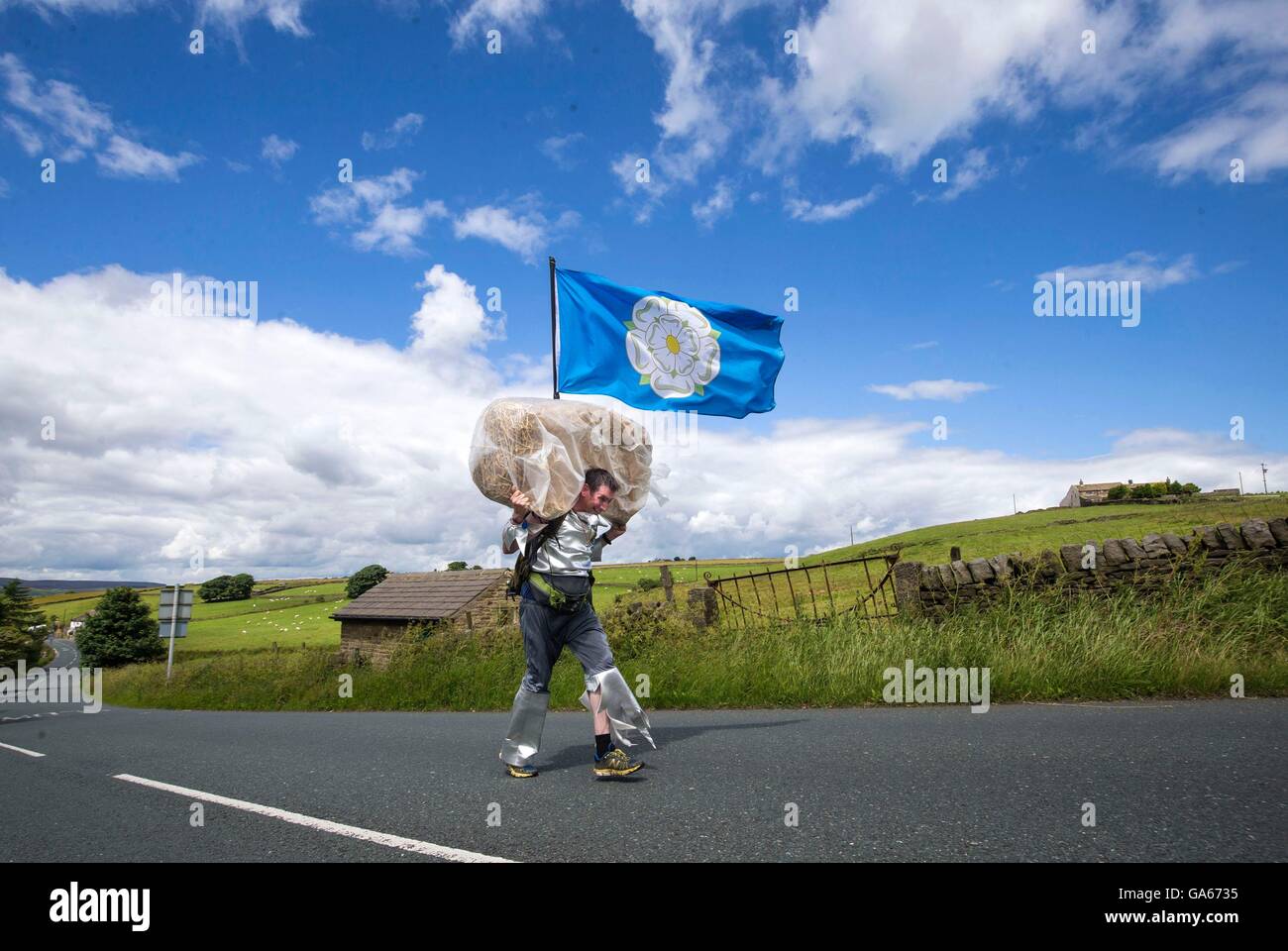 Un concurrent prend part à la ferme de la course de la paille dans le Yorkshire, qui consiste à courir en robe de soirée, tout en portant une botte de paille et se rendant sur chacune des pubs locaux dans le village pour récolter des fonds pour des œuvres de bienfaisance. Banque D'Images
