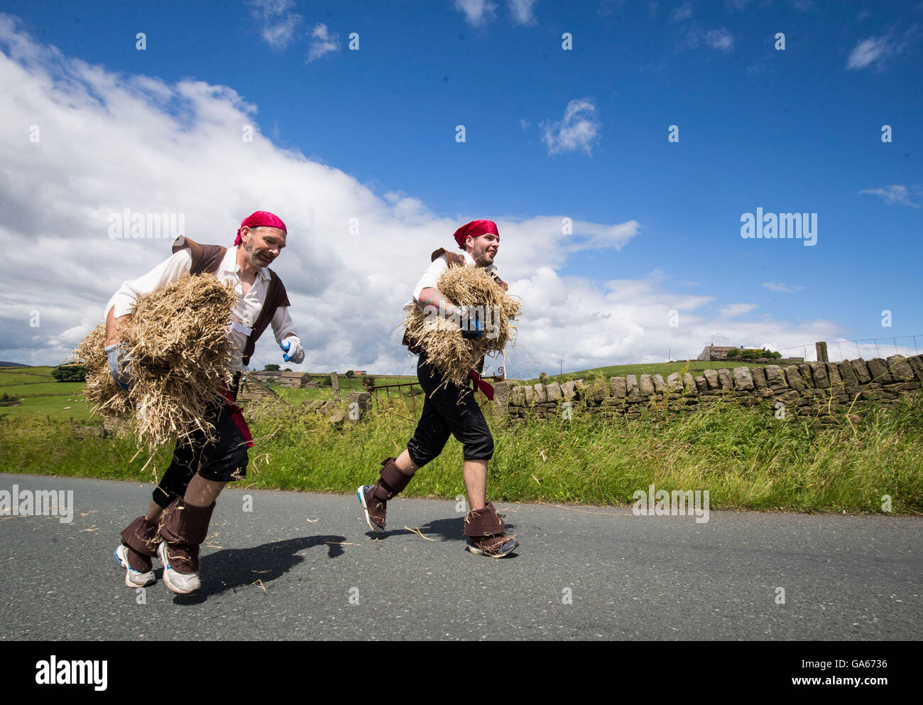 Concurrents prend part à la ferme de la course de la paille dans le Yorkshire, qui consiste à courir en robe de soirée, tout en portant une botte de paille et se rendant sur chacune des pubs locaux dans le village pour récolter des fonds pour des œuvres de bienfaisance. Banque D'Images
