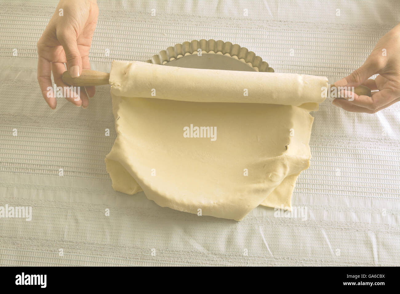 Femme plaçant stretched pâte crue avec un rouleau à pâtisserie sur une plaque de cuisson de la quiche Banque D'Images