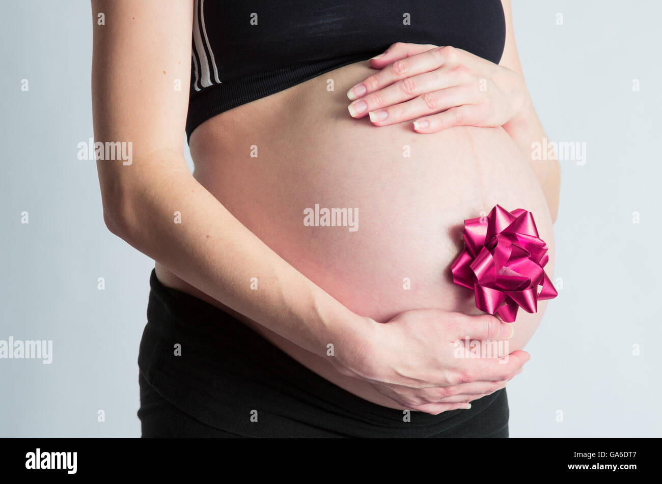 Une femme enceinte son cradels avec bow cadeau bébé ventre attaché. Banque D'Images