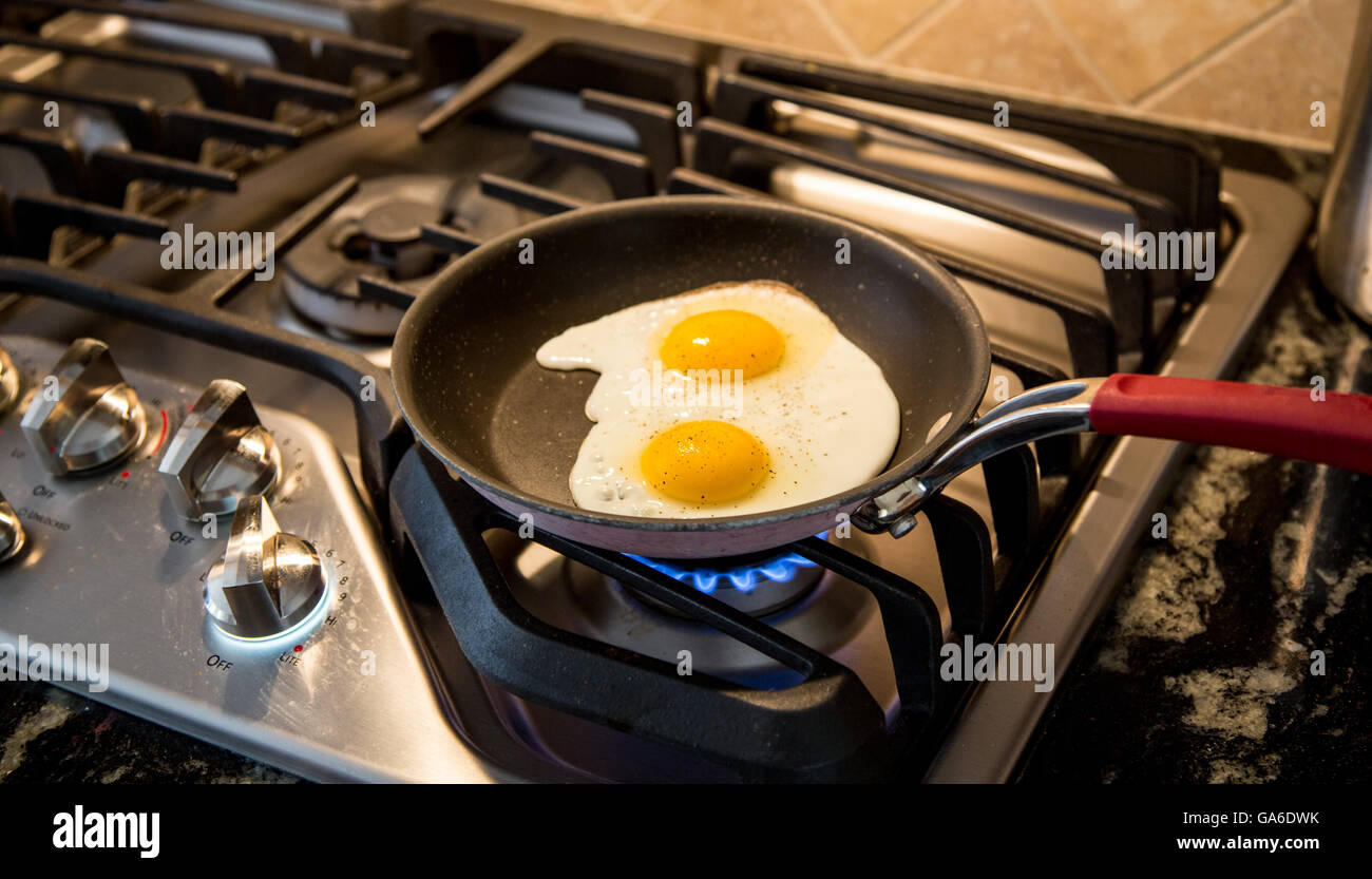Deux œufs d'être frit dans une poêle anti-adhésive sur une cuisinière à gaz. Banque D'Images