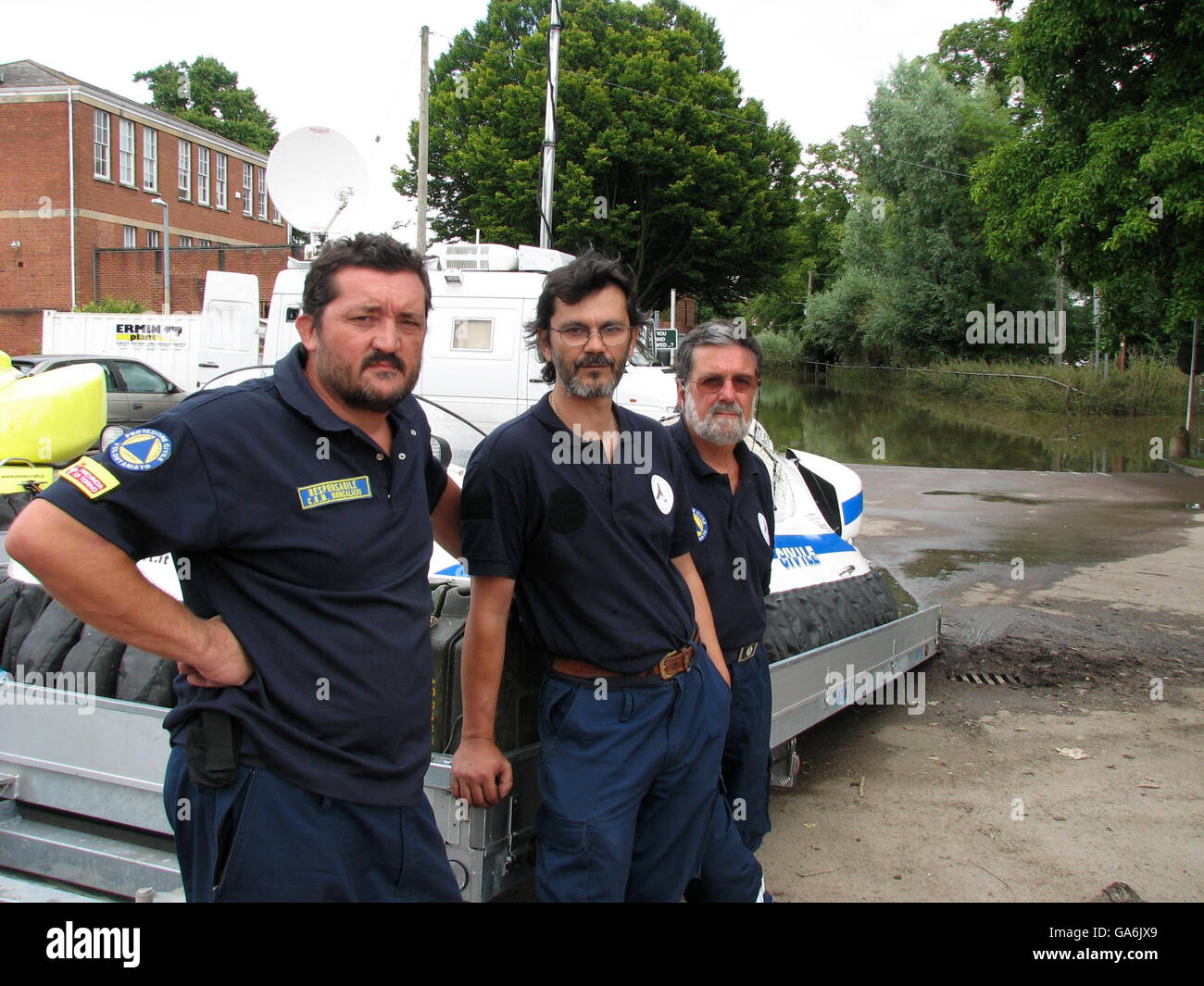 Trois volontaires italiens se tiennent à côté de leur aéroglisseur près d'un champ submergé à Tewkesbury où un corps a été découvert dans un parc. Banque D'Images