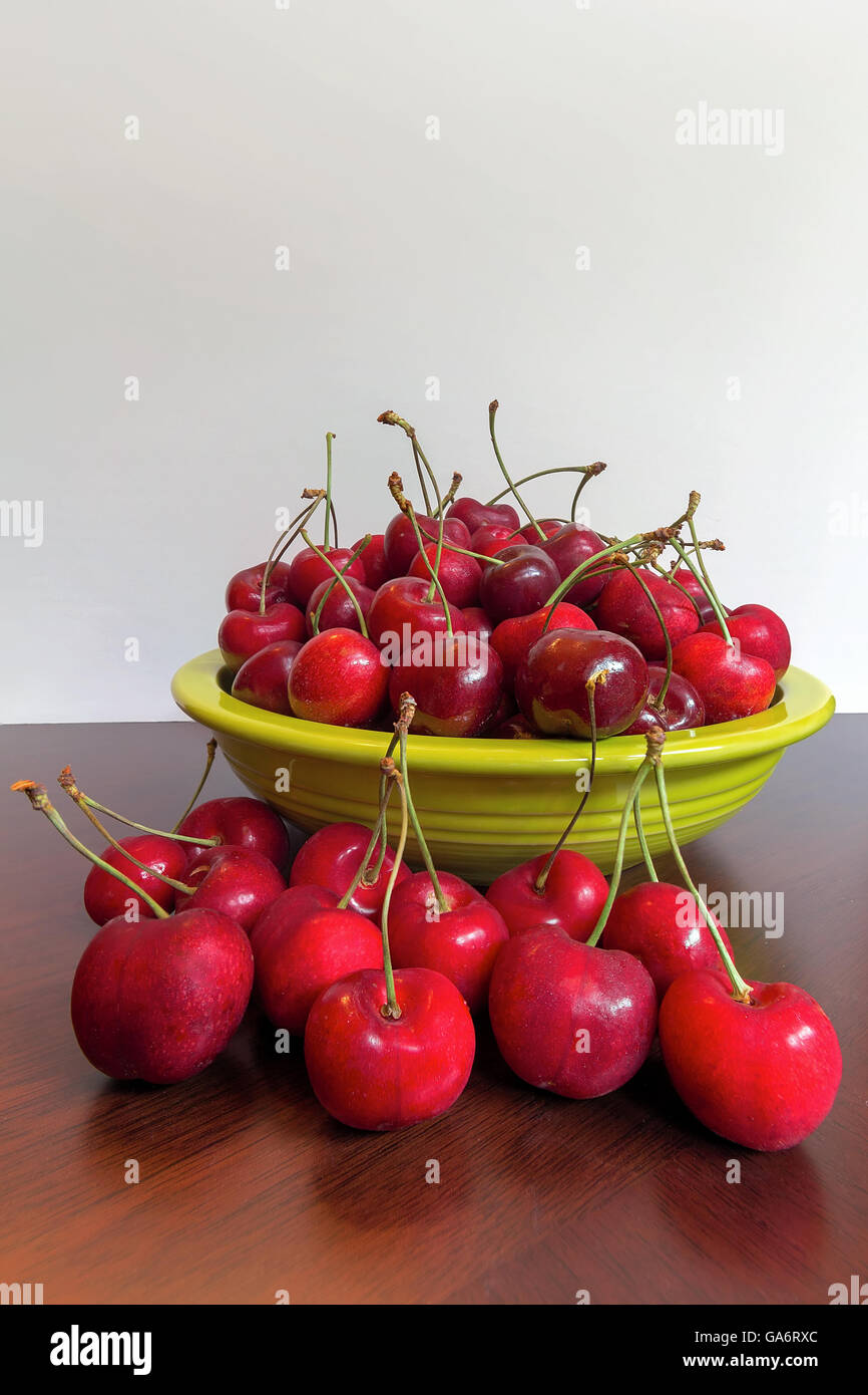 Cerises Bing dans un bol vert citron vert sur une table en bois Banque D'Images