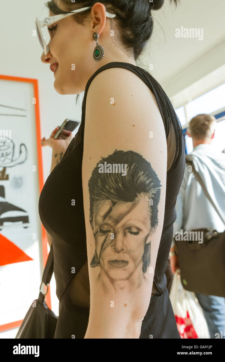 Jeune femme avec tatouage de David Bowie sur son bras portant des lunettes blanches Banque D'Images