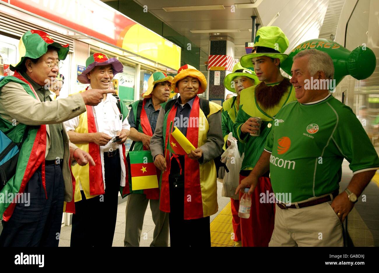 Les fans de football japonais qui soutiennent l'équipe du Cameroun, discutent avec les fans d'Irlande sur la plate-forme de la gare de Tokyo avant de faire le voyage à Niigata par Shinkansen (train à grande vitesse) Banque D'Images
