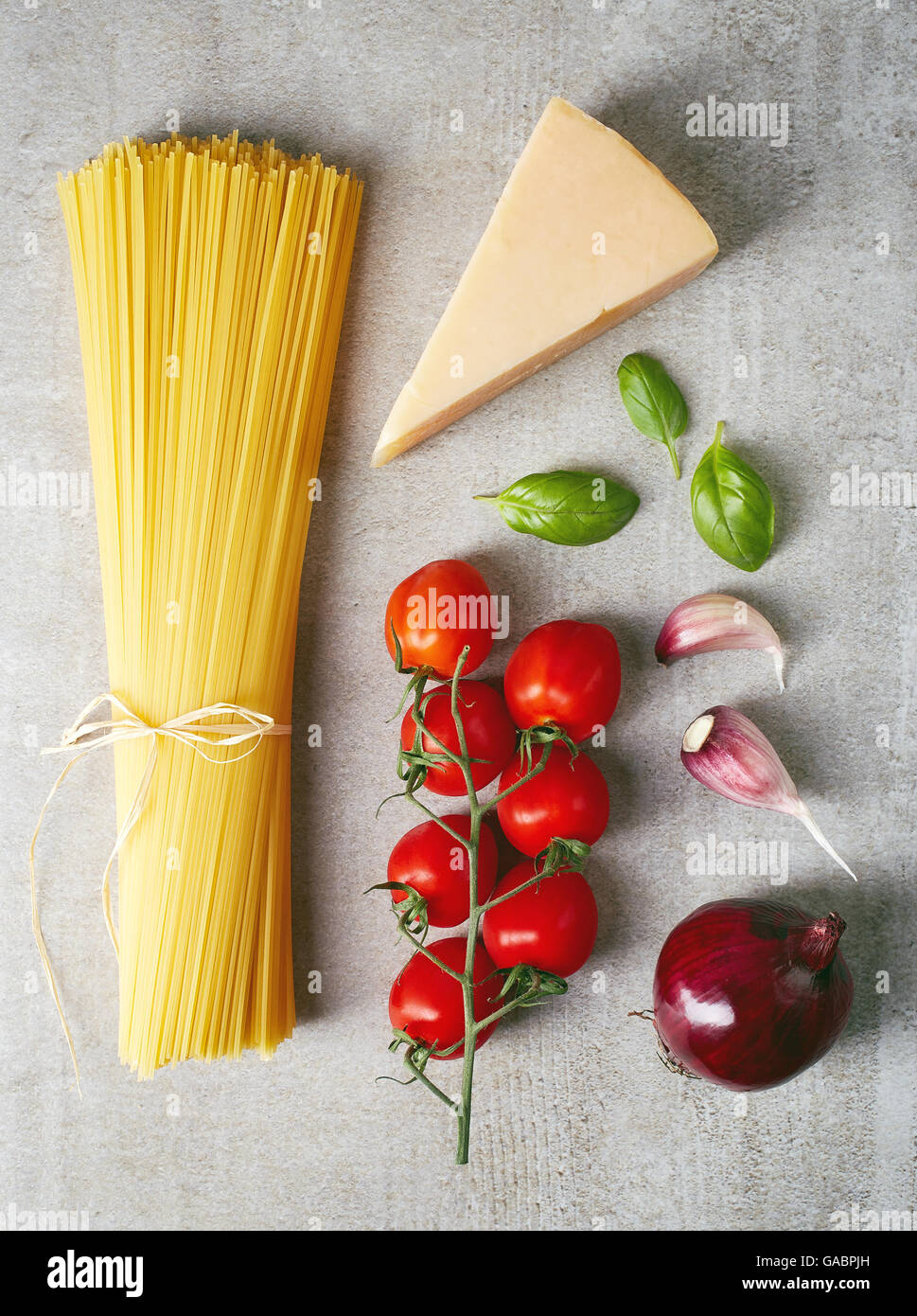 Les pâtes Spaghetti, tomates, fromage, l'oignon, l'ail et les feuilles de basilic sur table en pierre grise, vue du dessus Banque D'Images