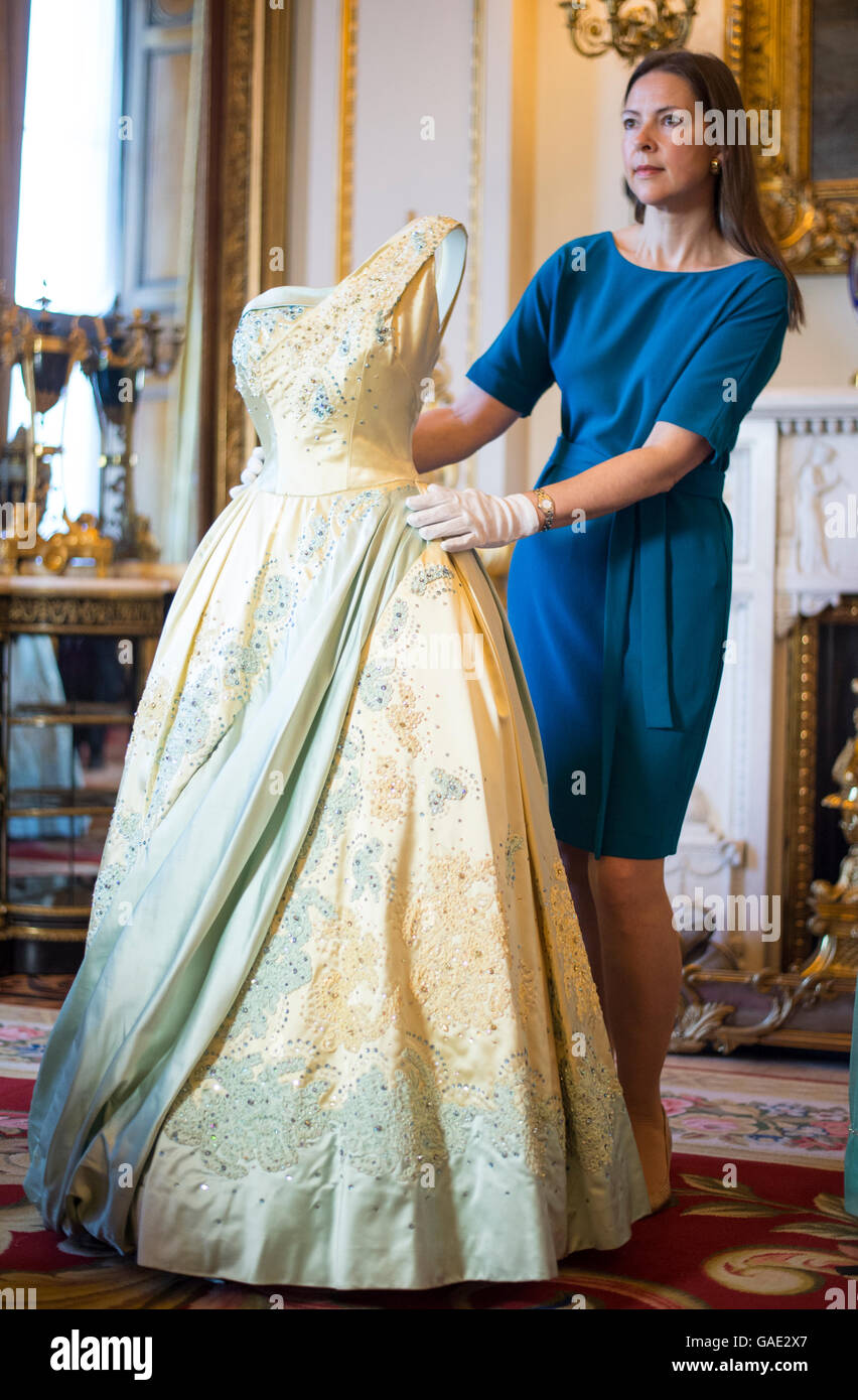 Curator Caroline de Guitaut ajuste une couleur bleu et or robe de soirée par Sir Norman Hartnell, portés par la reine sur une visite d'État aux Pays-Bas en 1958, au cours d'une presse d'aperçu pour la structuration d'un règne : 90 ans de style à partir de l'armoire de la Reine, une exposition au Palais de Buckingham à Londres. Banque D'Images