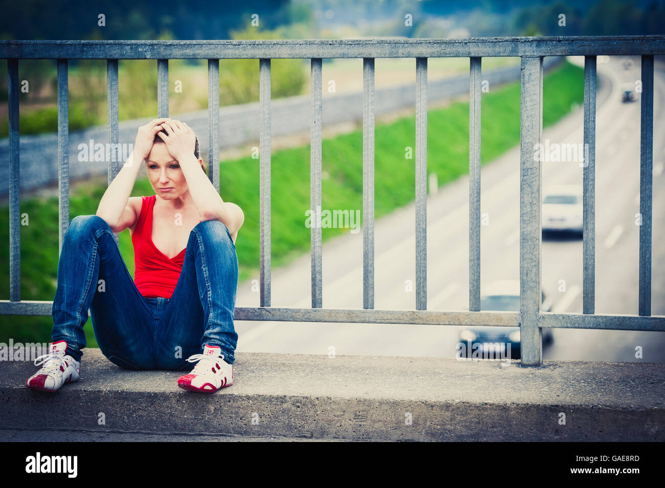 Jeune femme désespérée assis à un pont routier Banque D'Images
