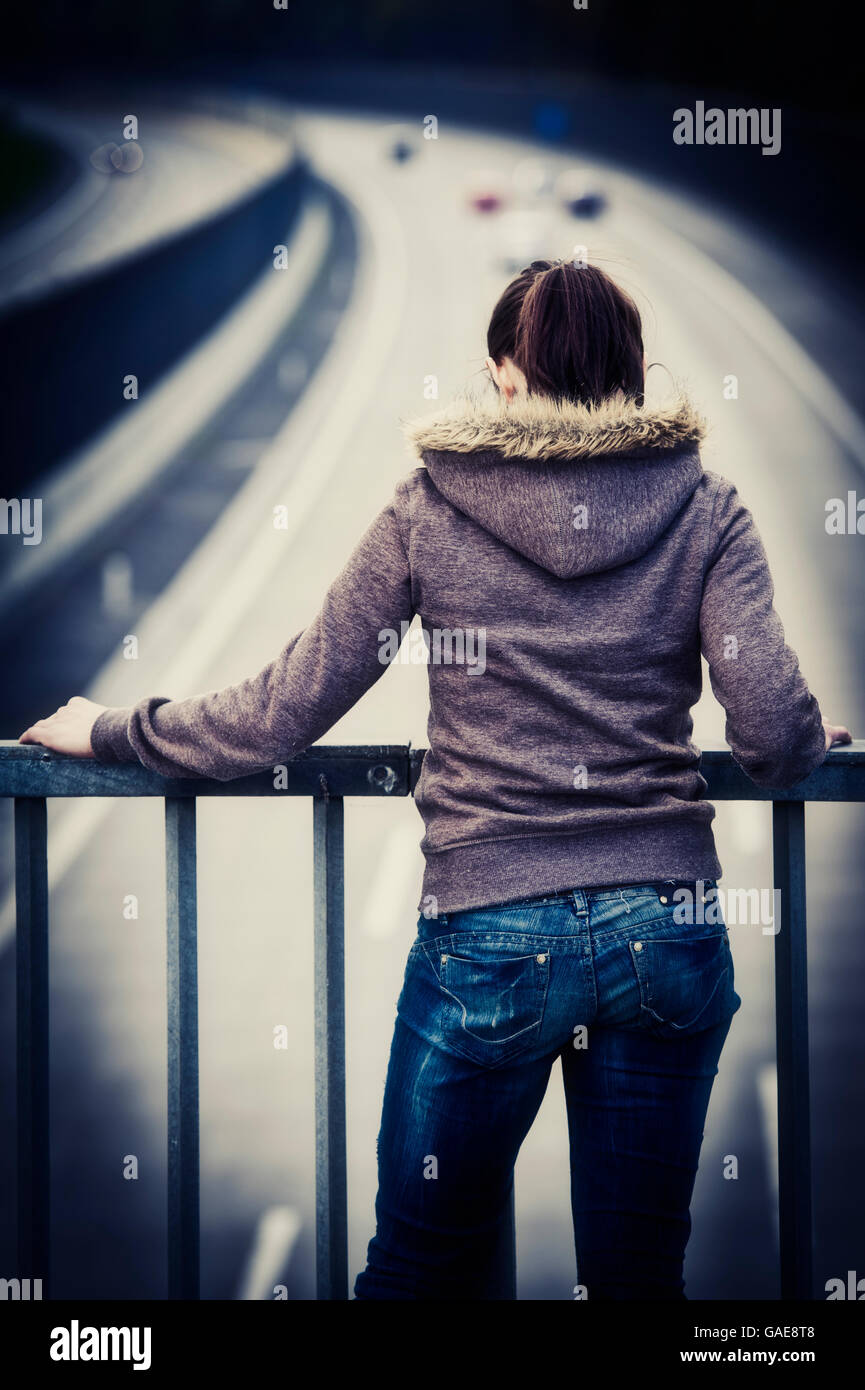 Femme debout à la rambarde d'un pont routier Banque D'Images