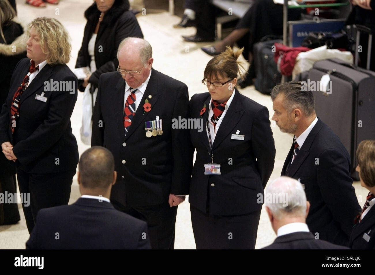Le personnel d'enregistrement de British Airways se tient pendant le silence de 2 minutes du dimanche du souvenir dans le terminal 1 de Heathrow, à l'ouest de Londres. Banque D'Images