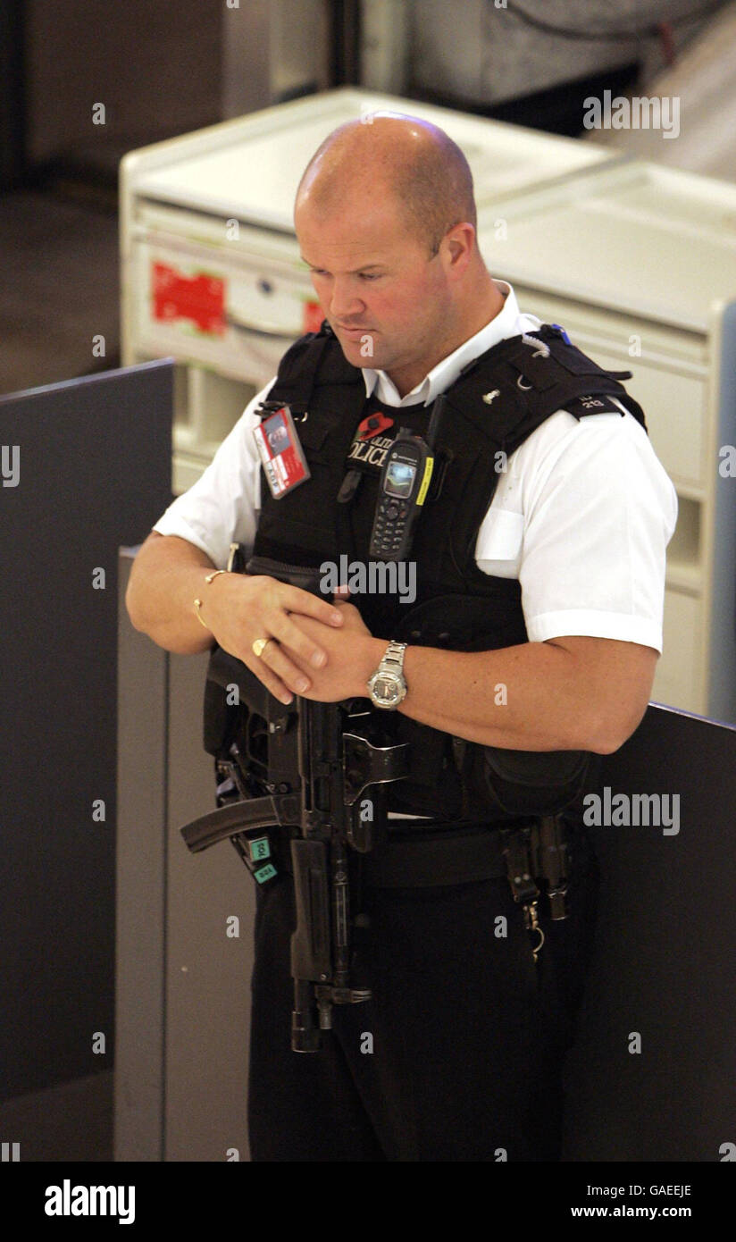 Un policier armé observe le silence de 2 minutes du dimanche du souvenir dans le terminal 1 de Heathrow, à l'ouest de Londres. Banque D'Images