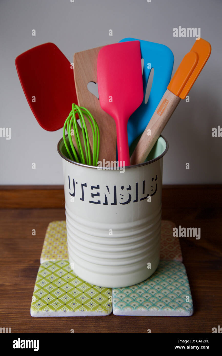 Les ustensiles de cuisine rétro pot sur comptoir en bois et tuiles avec 6 spatule de cuisson lumineux et colorés à l'aide d'un fouet et de cuillères pour cuisiner Banque D'Images