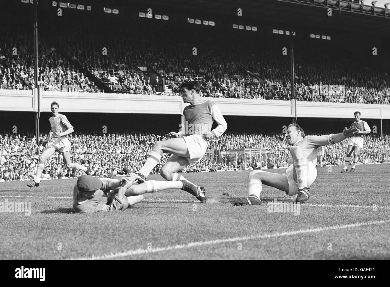 (G-D) le gardien de but de Manchester City, Bert Trautmann, plonge aux pieds d'Alan Skirton d'Arsenal, sous la surveillance de son coéquipier Dave Ewing Banque D'Images