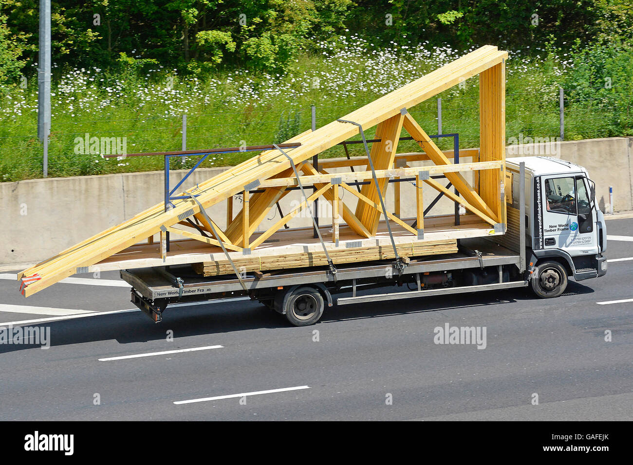 La logistique de transport des matériaux de construction via la chaîne d'camion chargé de bois assemblés en usine fermes de toit préfabriquées sur autoroute britannique Banque D'Images