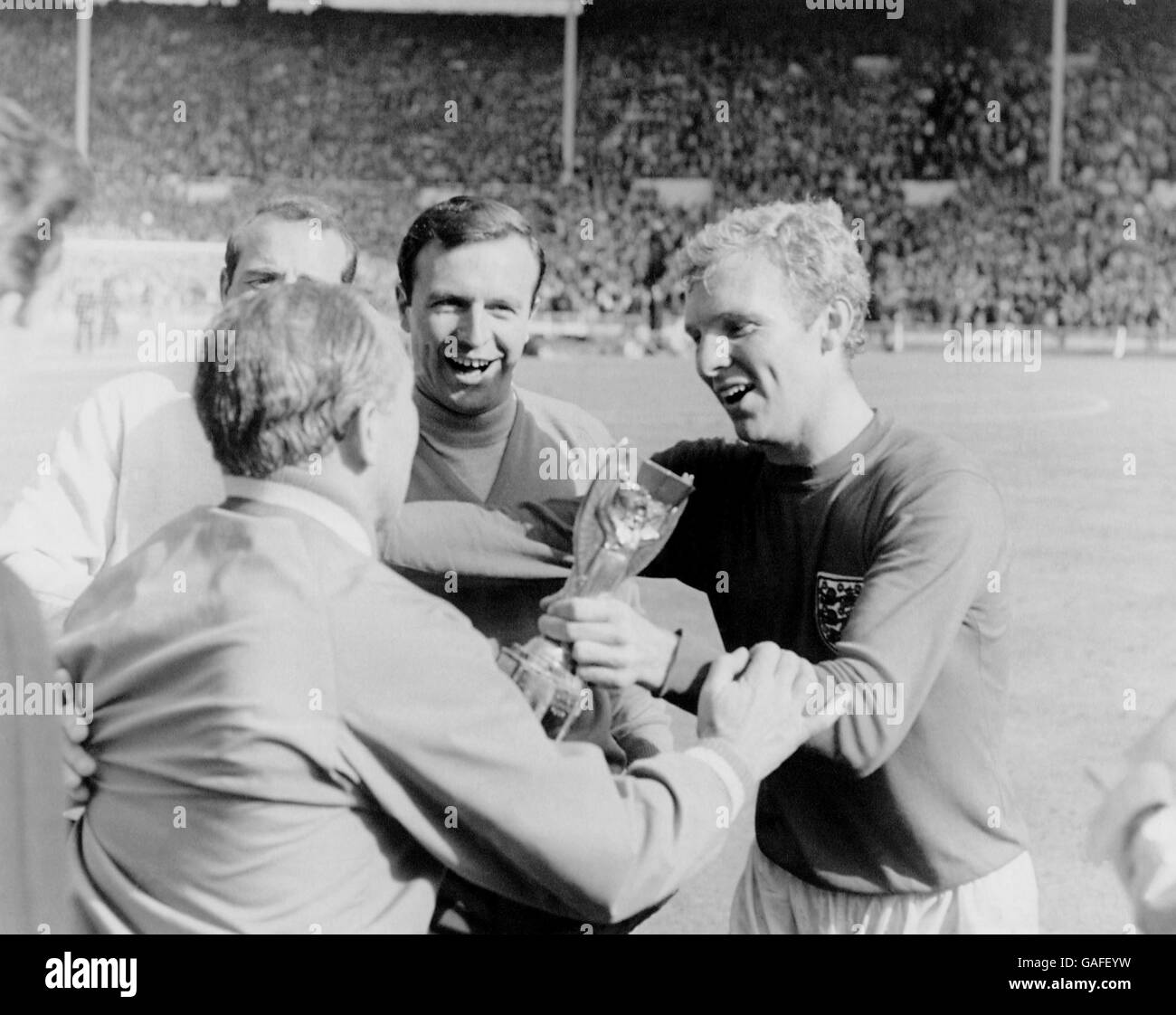 Le capitaine d'Angleterre Bobby Moore (r) remet le trophée Jules Rimet à son Manager Alf Ramsey (l) après la victoire de 4-2 en Angleterre, sous la surveillance de Jimmy Armfield (c) Banque D'Images