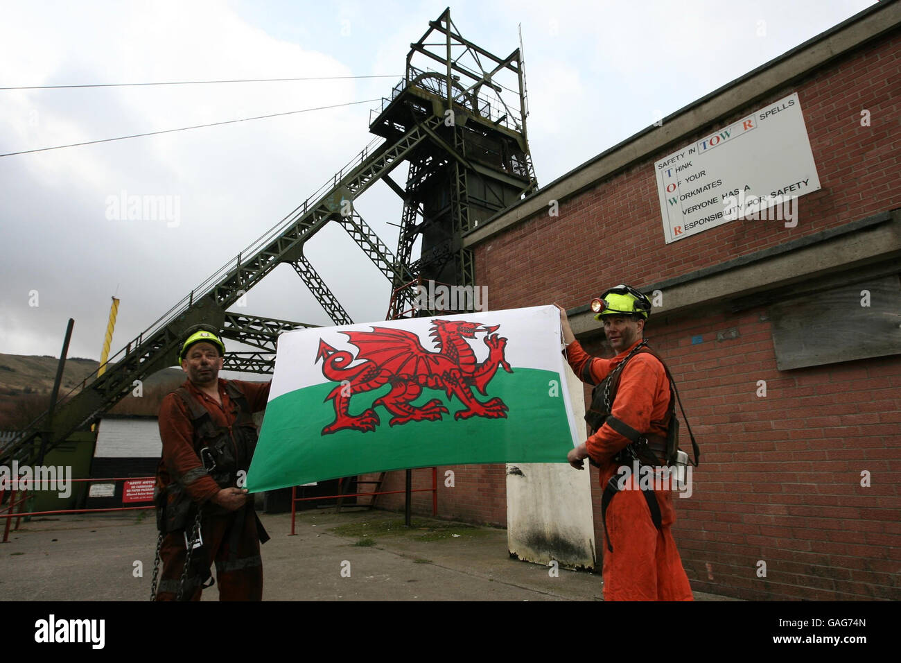 Les mineurs Garry Cutland et Billy Teague loft le drapeau gallois alors qu'ils terminent leur dernier quart de travail à la mine de charbon Tower à Hirwaun, Mid Glamorgan, pays de Galles. Banque D'Images