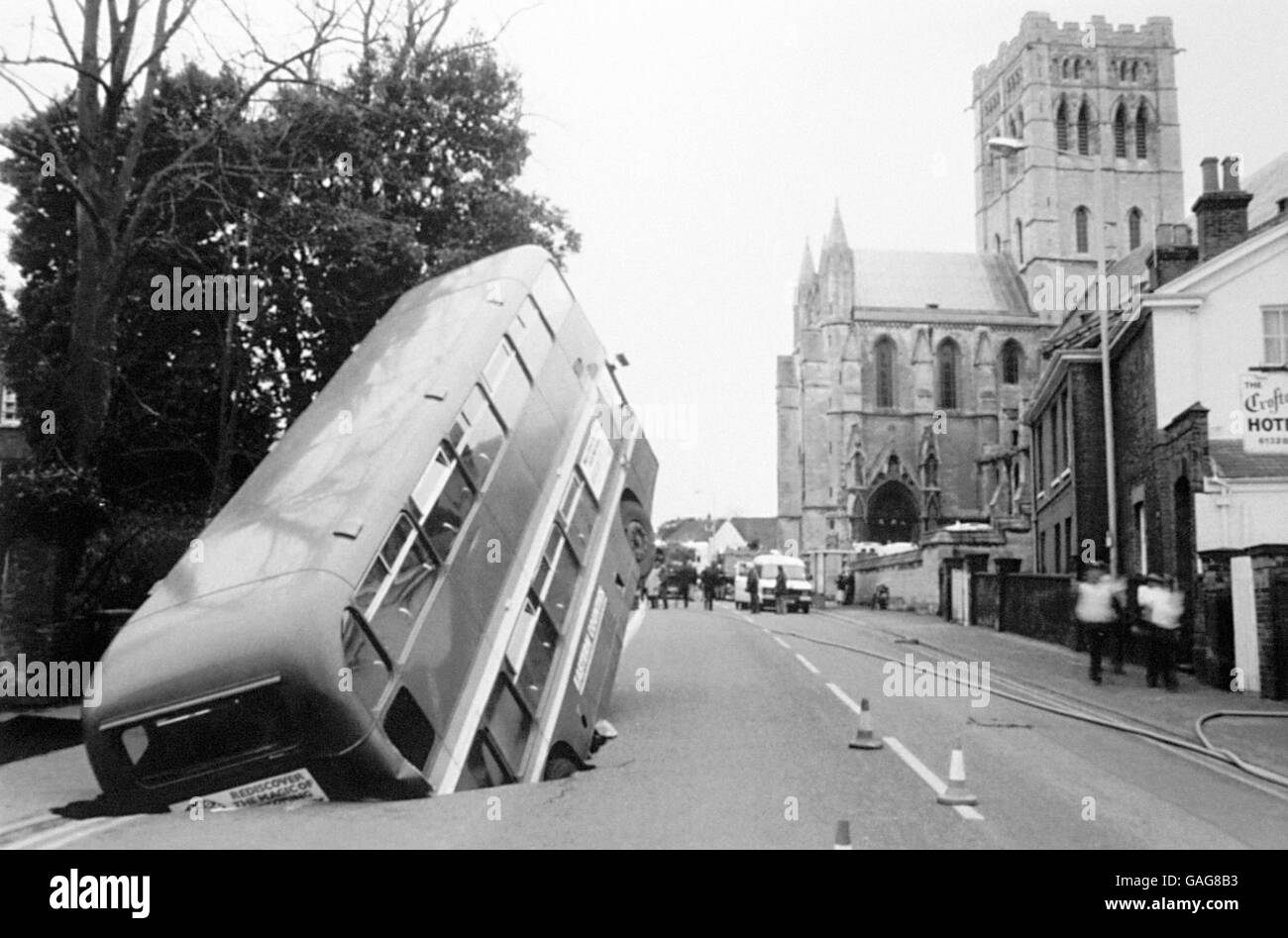 Transport - trous dans la route - Londres - 1983.Un bus londonien pointe vers le ciel après avoir fait marche arrière dans un grand trou de la route. Banque D'Images