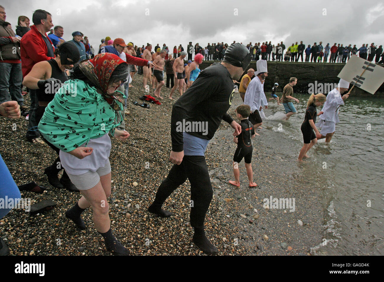 Les personnes en robe de fantaisie emprennent la mer au port de Wicklow pendant une baignade caritative du jour de l'an organisée par les Blue Dolphins et le club de natation de Wicklow. Banque D'Images