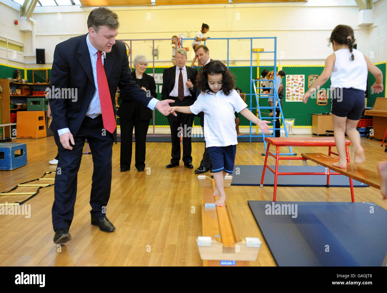 Ed Balls, secrétaire d'État à l'enfance, à l'école et à la famille, aide Silsila Darwish, âgée de 4 ans, à passer un faisceau de croisement lors de son cours d'exercice à l'école primaire Green Dragon, Brentford, sous la surveillance d'Alan Johnson (au centre arrière), qui a annoncé une stratégie pangouvernementale de lutte contre l'obésité. Banque D'Images