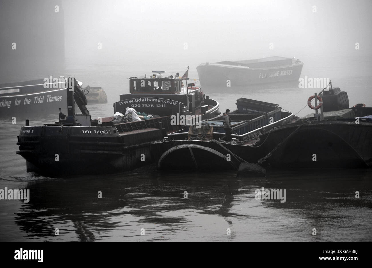 Un bateau de rivière travaille sur la Tamise, près de la rive sud dans le brouillard du matin. Banque D'Images