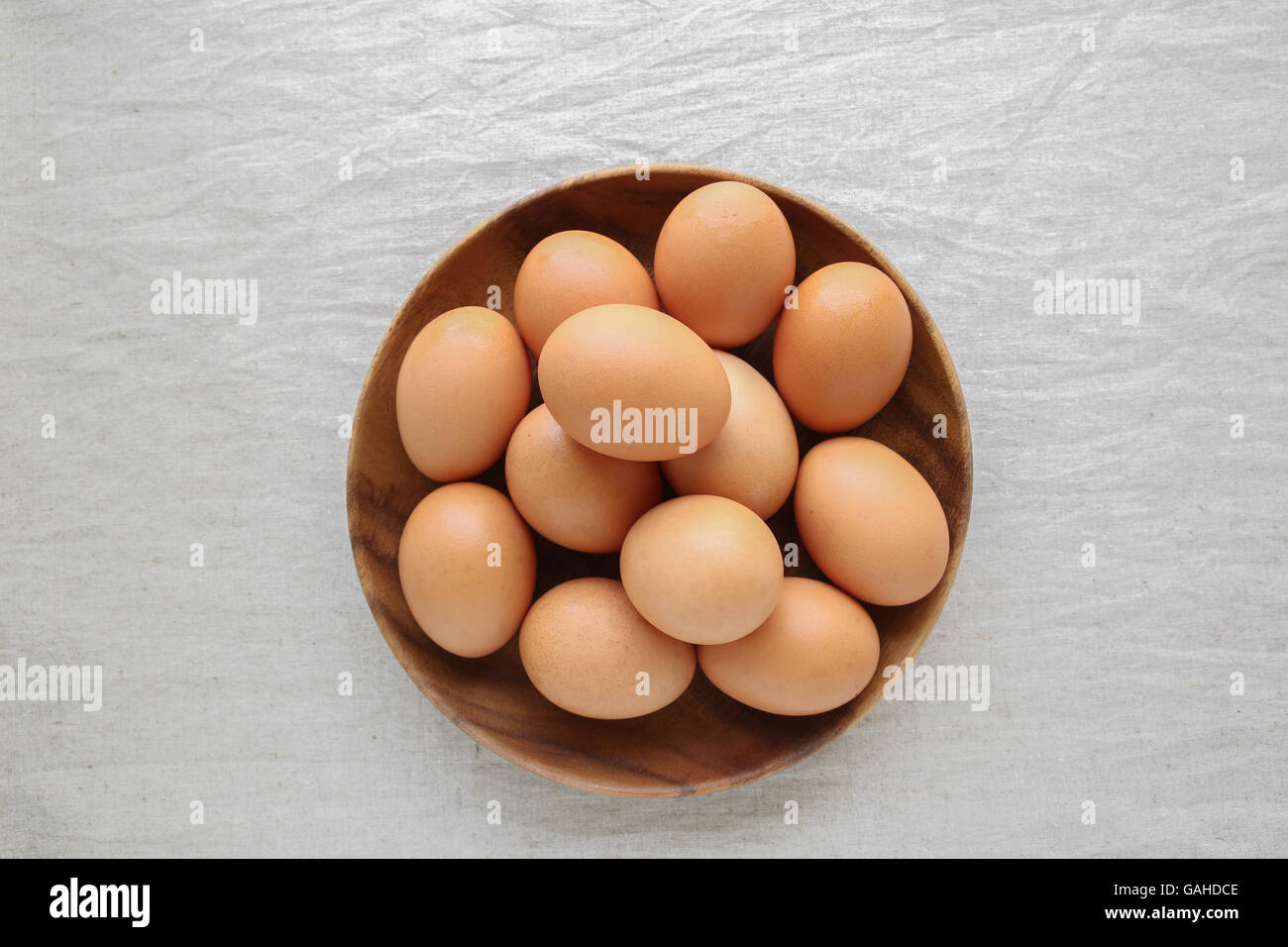 Oeufs dans le bol en bois sur fond de lin Banque D'Images