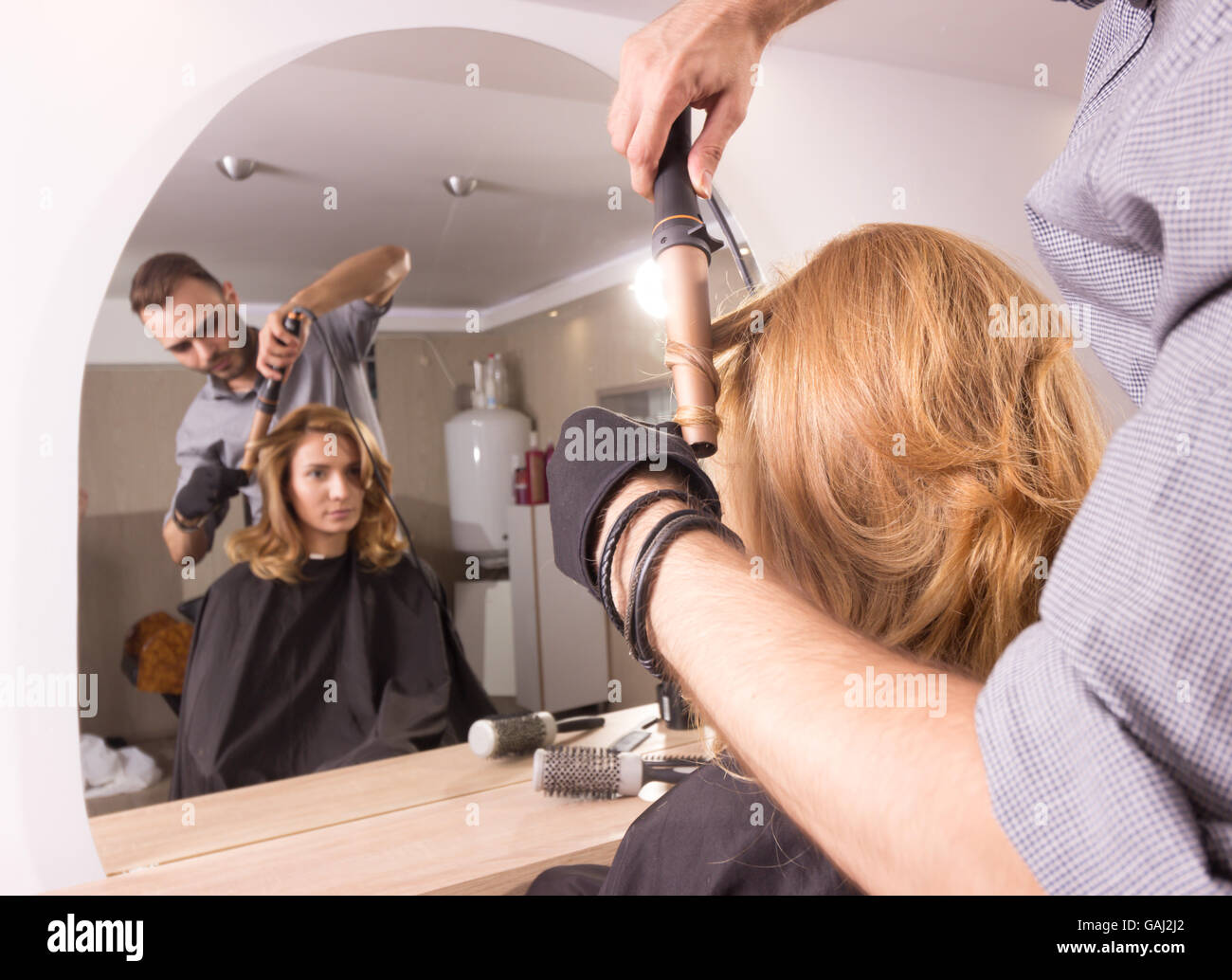 Hairstylist curling cheveux fer libre, vue arrière. Banque D'Images