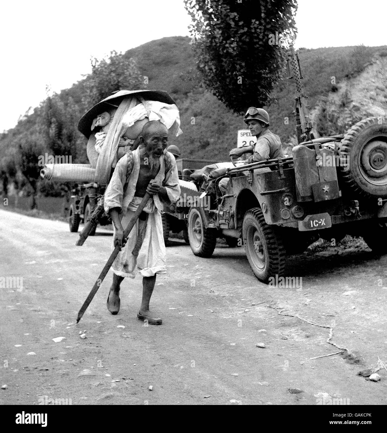 Le soldat AMÉRICAIN en poste pour la première ligne observe que ce réfugié âgé fuit les troupes nord-coréennes en avance. L'homme a toutes ses possions mondaines sur son dos alors qu'il cherche la sécurité. Banque D'Images Le soldat AMÉRICAIN en poste pour la première ligne observe que ce réfugié âgé fuit les troupes nord-coréennes en avance. L'homme a toutes ses possions mondaines sur son dos alors qu'il cherche la sécurité. Banque D'Images