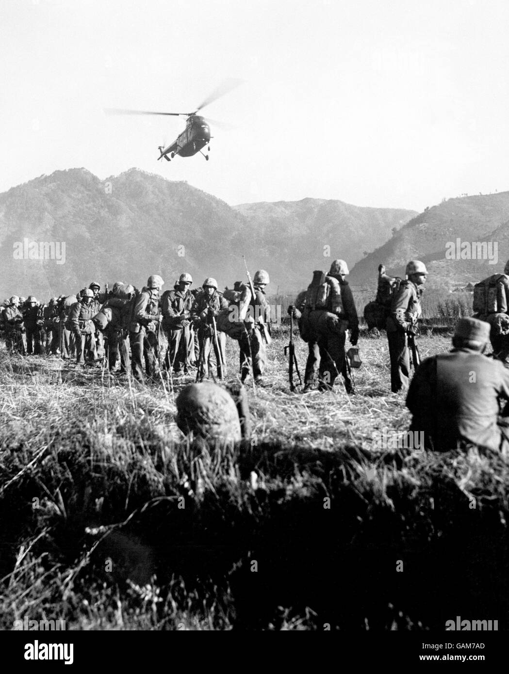 L'hélicoptère de transport maritime américain transporte une charge de Marines américains fatigués par la bataille dans une zone arrière en Corée, tandis que sur le sol, les troupes de secours attendent le signal de décollage pour remplacer les hommes en première ligne.Jusqu'à présent, des hélicoptères étaient utilisés dans la plus grande opération de « secours de trous de bœuf » de la guerre de Corée.Plus de 2000 « tortues luths » ont été transportées entre les lignes avant et arrière. Banque D'Images