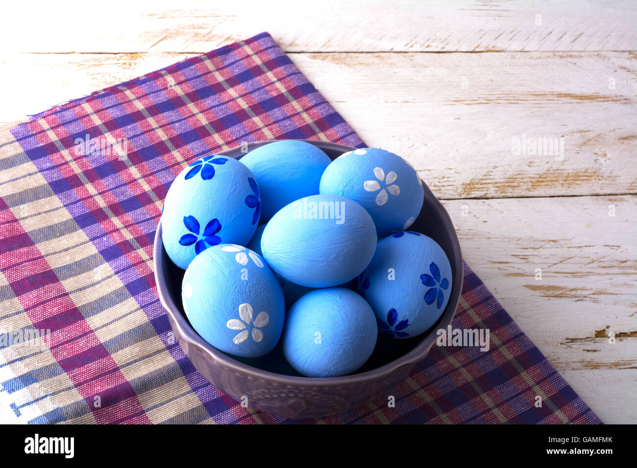 Les oeufs de Pâques bleu violet dans un bol sur une serviette à carreaux sur un fond de bois blanc. Easter Banque D'Images