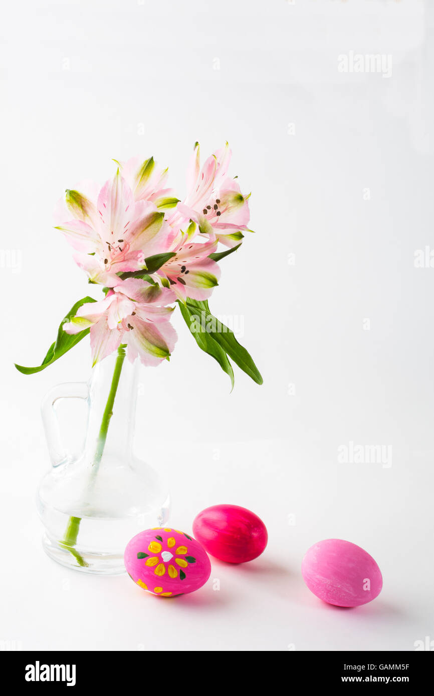 Pâques oeufs rose peint à la main avec des fleurs roses délicates dans un vase de verre sur fond blanc. Arrière-plan de Pâques. Easter sy Banque D'Images
