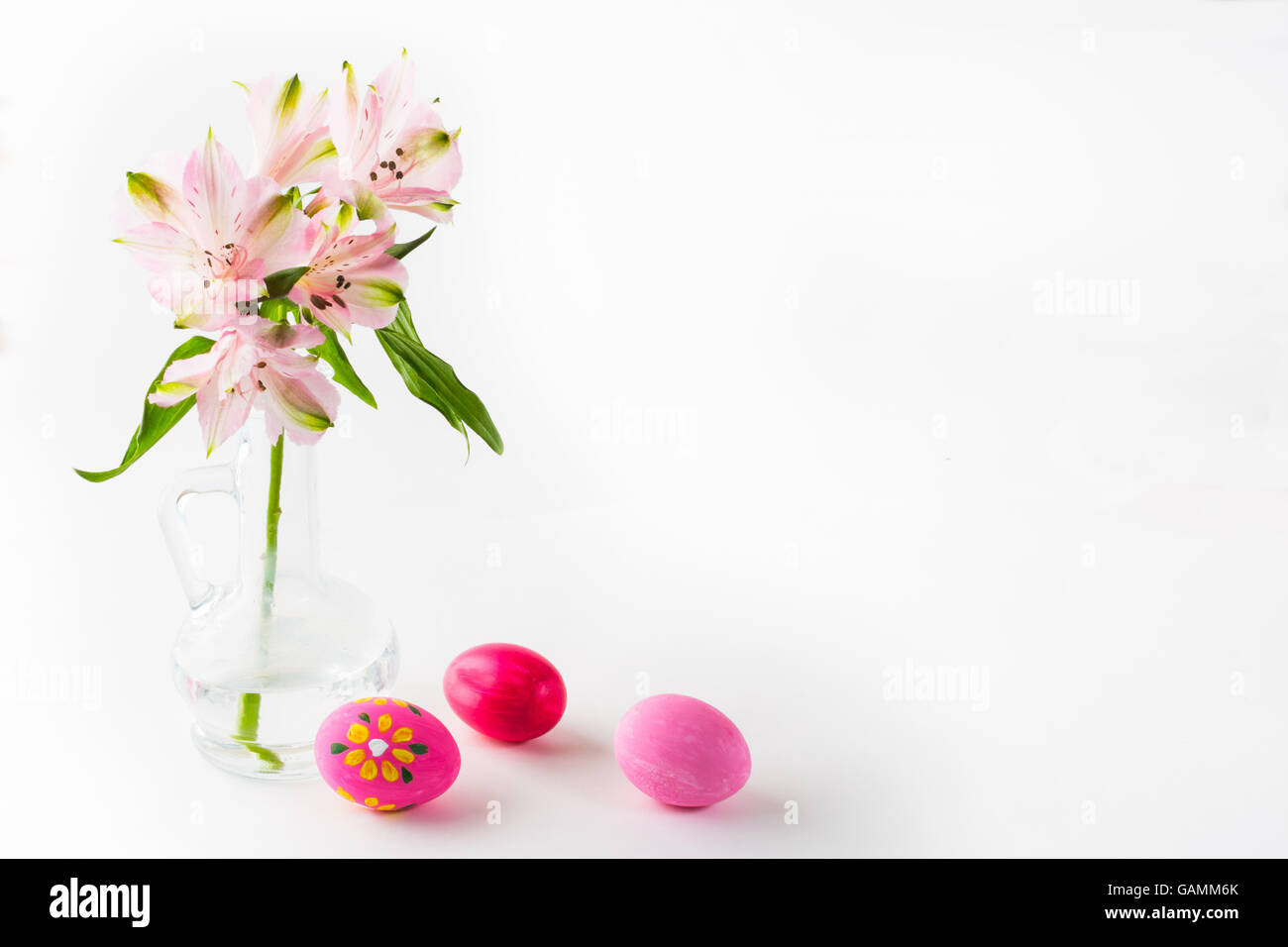 Rose peint à la main les oeufs de Pâques avec des fleurs roses délicates dans un vase de verre sur fond blanc. Arrière-plan de Pâques. Easter sy Banque D'Images