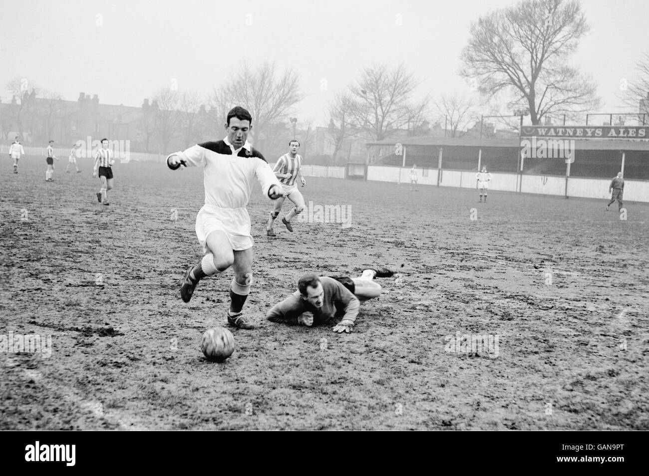 Eddie Firmani de Charlton Athletic (l) dribbles autour du gardien de but de Clapton pendant un match d'entraînement, destiné à aider Clapton dans la construction de leur match de la coupe amateur contre Barnett Banque D'Images