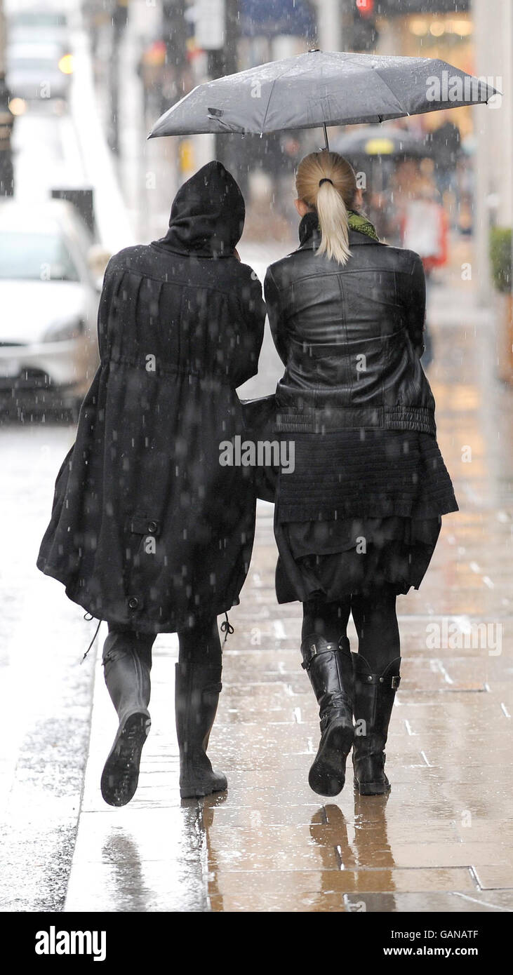 Une paire de femmes se cache devant les chutes de pluie dans le centre de Londres. Banque D'Images